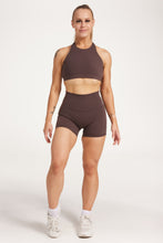 Load image into Gallery viewer, Buttery soft high waisted women&#39;s gym shorts with 4&quot; inseam with curved stitched detailing for a butt shaping effect, and no front rise seam, paired with a high neck women&#39;s sports bra with a supportive elasticated hem and triple layered fabric with removable pads for extra support and crossover back straps in Dark Chocolate.
