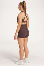 Load image into Gallery viewer, Buttery soft high waisted women&#39;s gym shorts with 4&quot; inseam with curved stitched detailing for a butt shaping effect, and no front rise seam, paired with a high neck women&#39;s sports bra with a supportive elasticated hem and triple layered fabric with removable pads for extra support and crossover back straps in Dark Chocolate.
