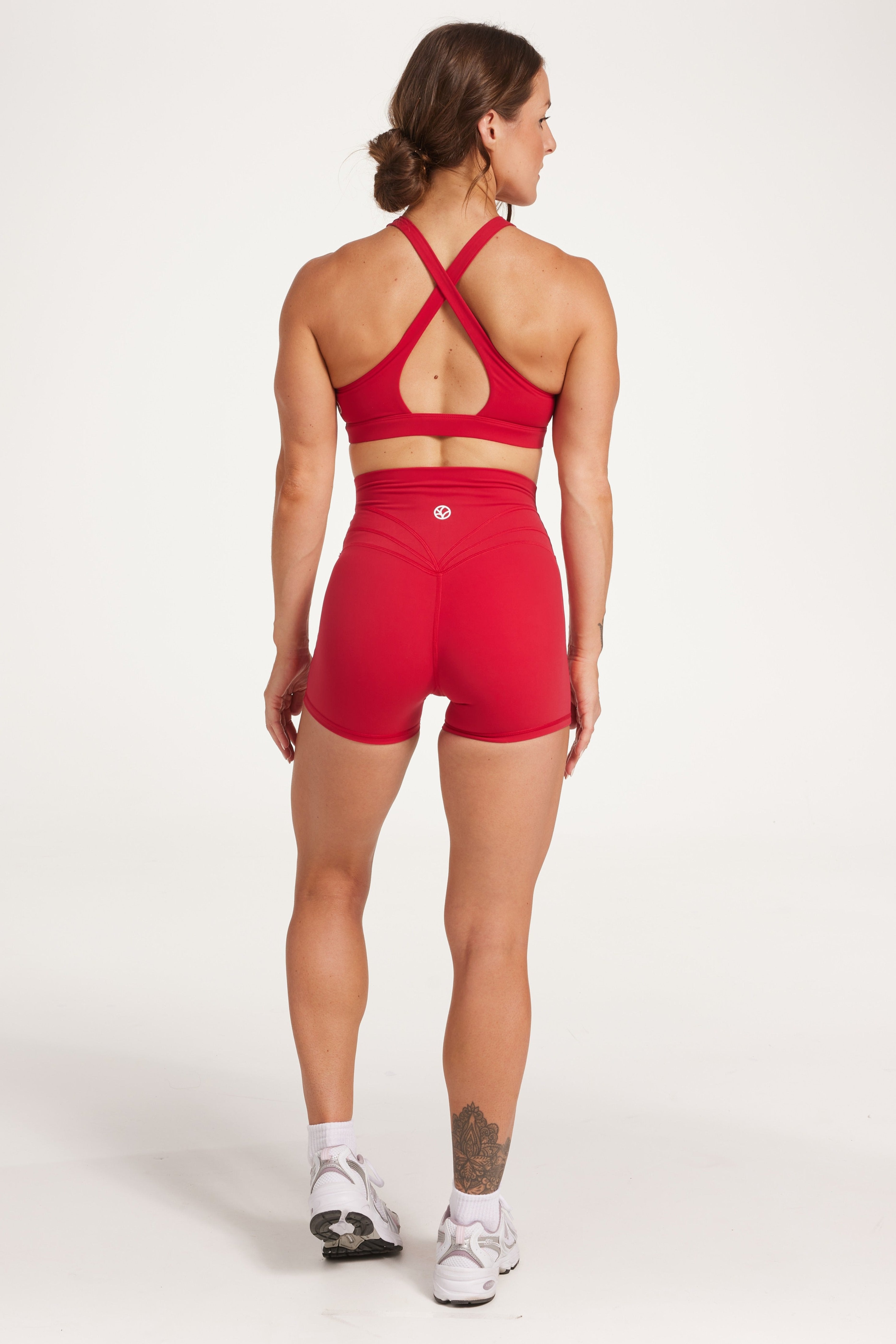 Buttery soft high waisted women's gym shorts with 4" inseam with curved stitched detailing for a butt shaping effect, and no front rise seam, paired with a high neck women's sports bra with a supportive elasticated hem and triple layered fabric with removable pads for extra support and crossover back straps in Raspberry red.