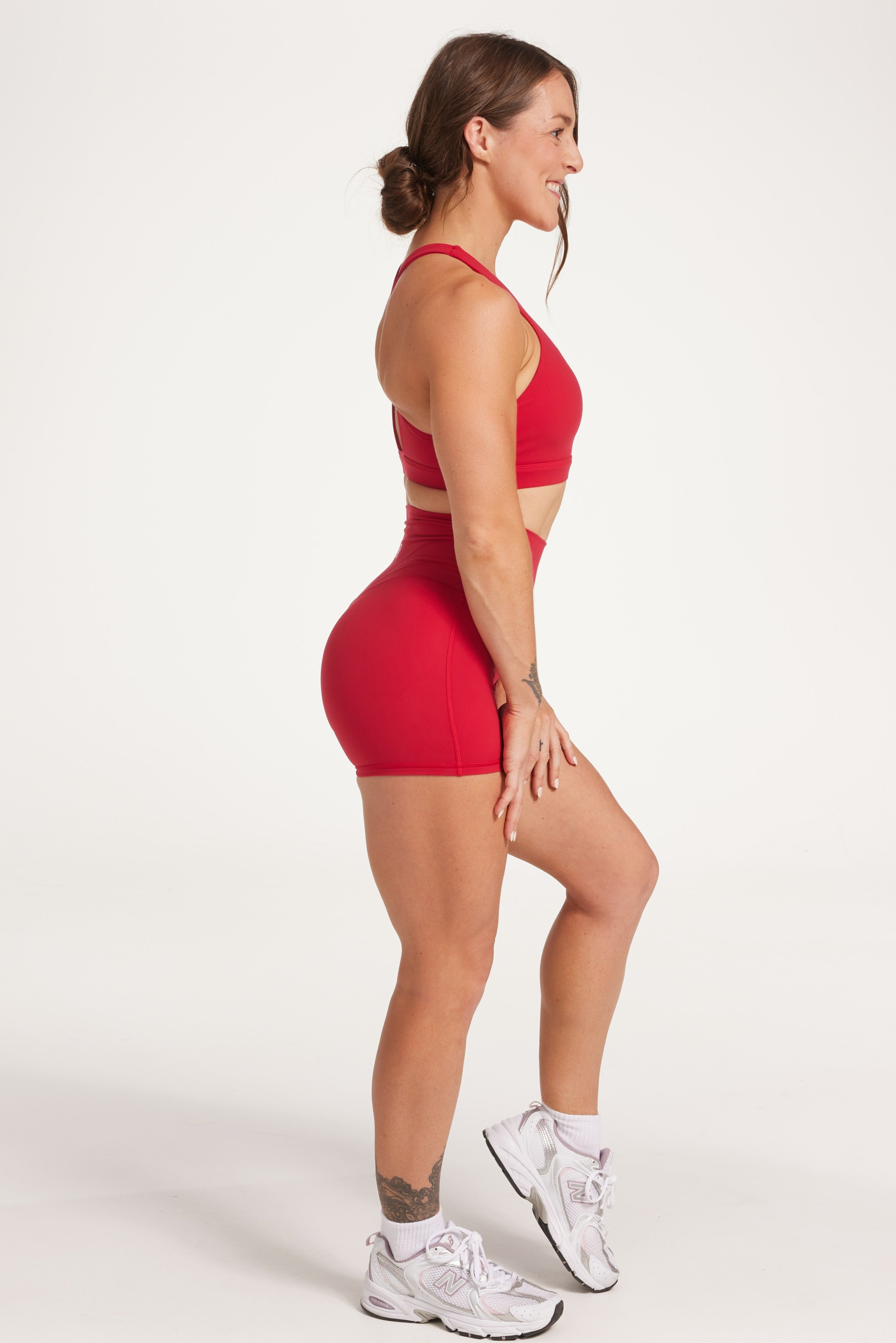 Buttery soft high waisted women's gym shorts with 4" inseam with curved stitched detailing for a butt shaping effect, and no front rise seam, paired with a high neck women's sports bra with a supportive elasticated hem and triple layered fabric with removable pads for extra support and crossover back straps in Raspberry red.