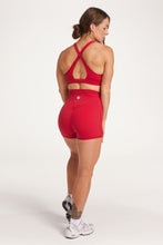 Load image into Gallery viewer, Buttery soft high waisted women&#39;s gym shorts with 4&quot; inseam with curved stitched detailing for a butt shaping effect, and no front rise seam, paired with a high neck women&#39;s sports bra with a supportive elasticated hem and triple layered fabric with removable pads for extra support and crossover back straps in Raspberry red.
