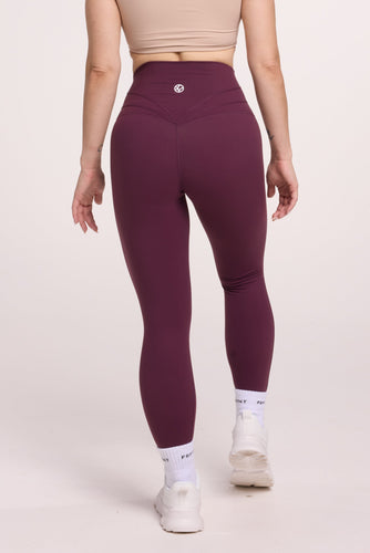 Buttery soft high waisted women's gym tights with curved back seam stitched detailing for a butt shaping effect, and no front rise seam, in plum purple paired with an V neck women's crop t-shirt with a supportive elasticated hem and triple layered fabric with removable pads for extra support in beige