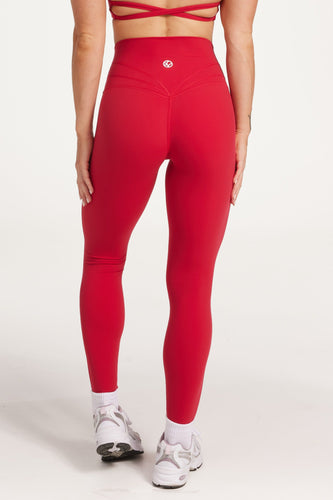 Buttery soft high waisted women's gym tights with curved hem stitched detailing for a butt shaping effect, and no front rise seam, paired with an open back women's crop t-shirt with a supportive elasticated hem and triple layered fabric with removable pads for extra support and aesthetic cross back straps in Raspberry red.