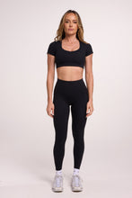 Load image into Gallery viewer, Buttery soft high waisted women&#39;s gym tights with practical pockets, sweetheart back seams for an upper glute shaping effect, and no front rise seam, paired with an V neck women&#39;s crop t-shirt with a supportive elasticated hem and triple layered fabric with removable pads for extra support in black
