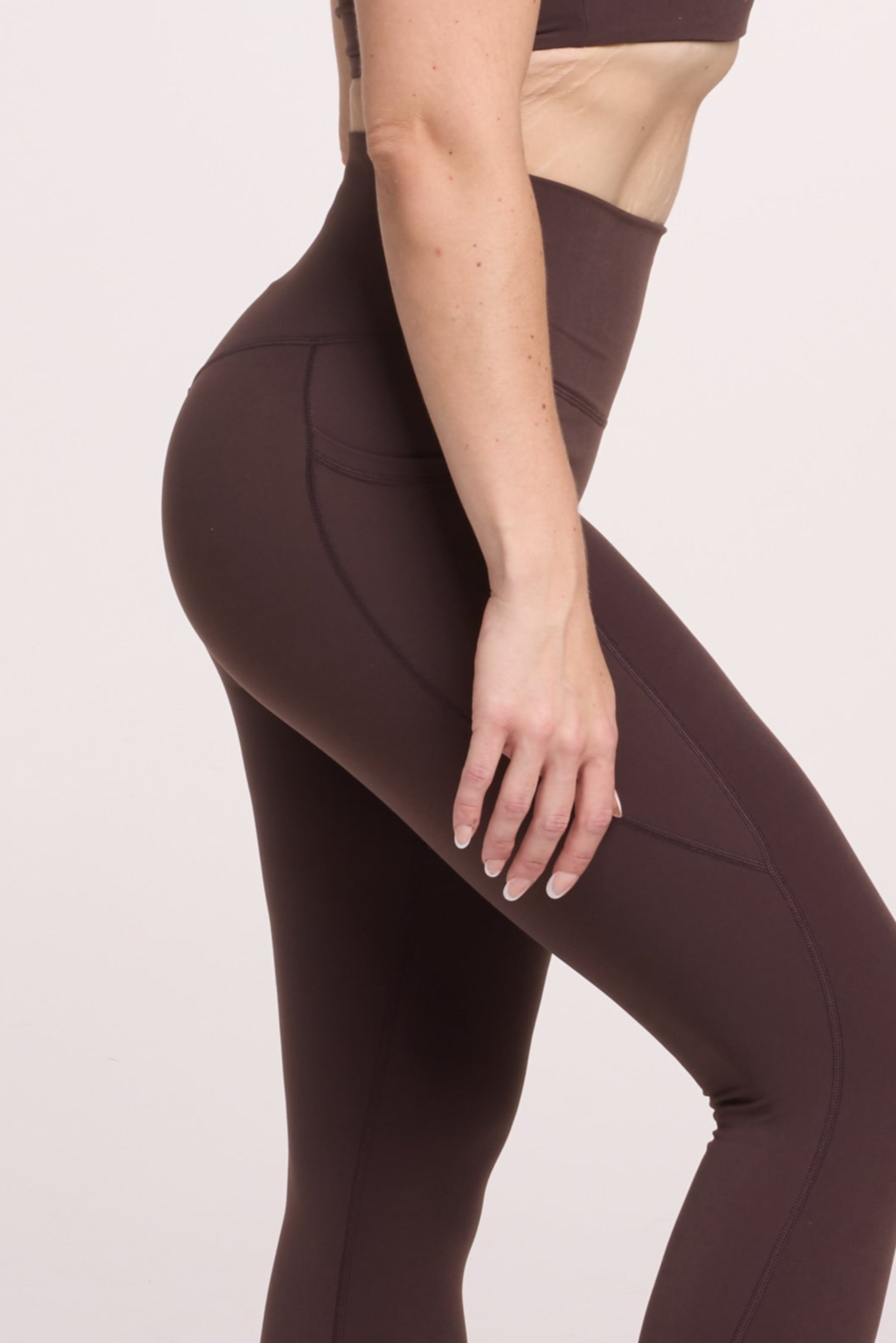 Buttery soft high waisted women's gym tights with practical pockets, sweetheart back seams for an upper glute shaping effect, and no front rise seam, paired with an V neck women's crop t-shirt with a supportive elasticated hem and triple layered fabric with removable pads for extra support in chocolate