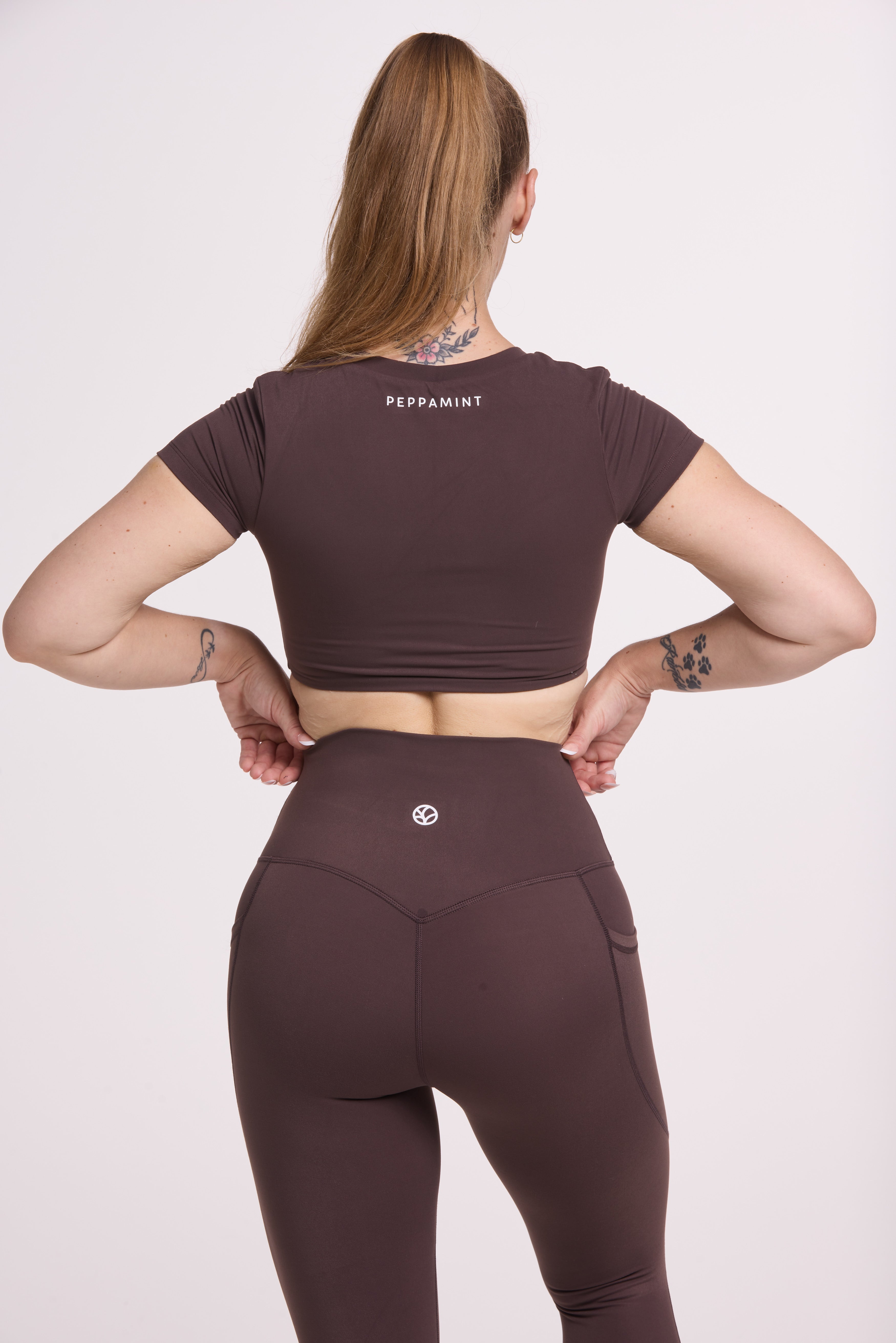 Buttery soft high waisted women's gym tights with practical pockets, sweetheart back seams for an upper glute shaping effect, and no front rise seam, paired with an V neck women's crop t-shirt with a supportive elasticated hem and triple layered fabric with removable pads for extra support in chocolate
