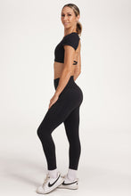 Load image into Gallery viewer, Buttery soft high waisted women&#39;s gym tights with curved hem stitched detailing for a butt shaping effect, and no front rise seam, paired with an open back women&#39;s crop t-shirt with a supportive elasticated hem and triple layered fabric with removable pads for extra support and aesthetic cross back straps in Black.
