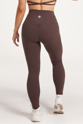 Buttery soft high waisted women's gym tights with curved hem stitched detailing for a butt shaping effect, and no front rise seam, paired with an open back women's crop t-shirt with a supportive elasticated hem and triple layered fabric with removable pads for extra support and aesthetic cross back straps in dark chocolate.