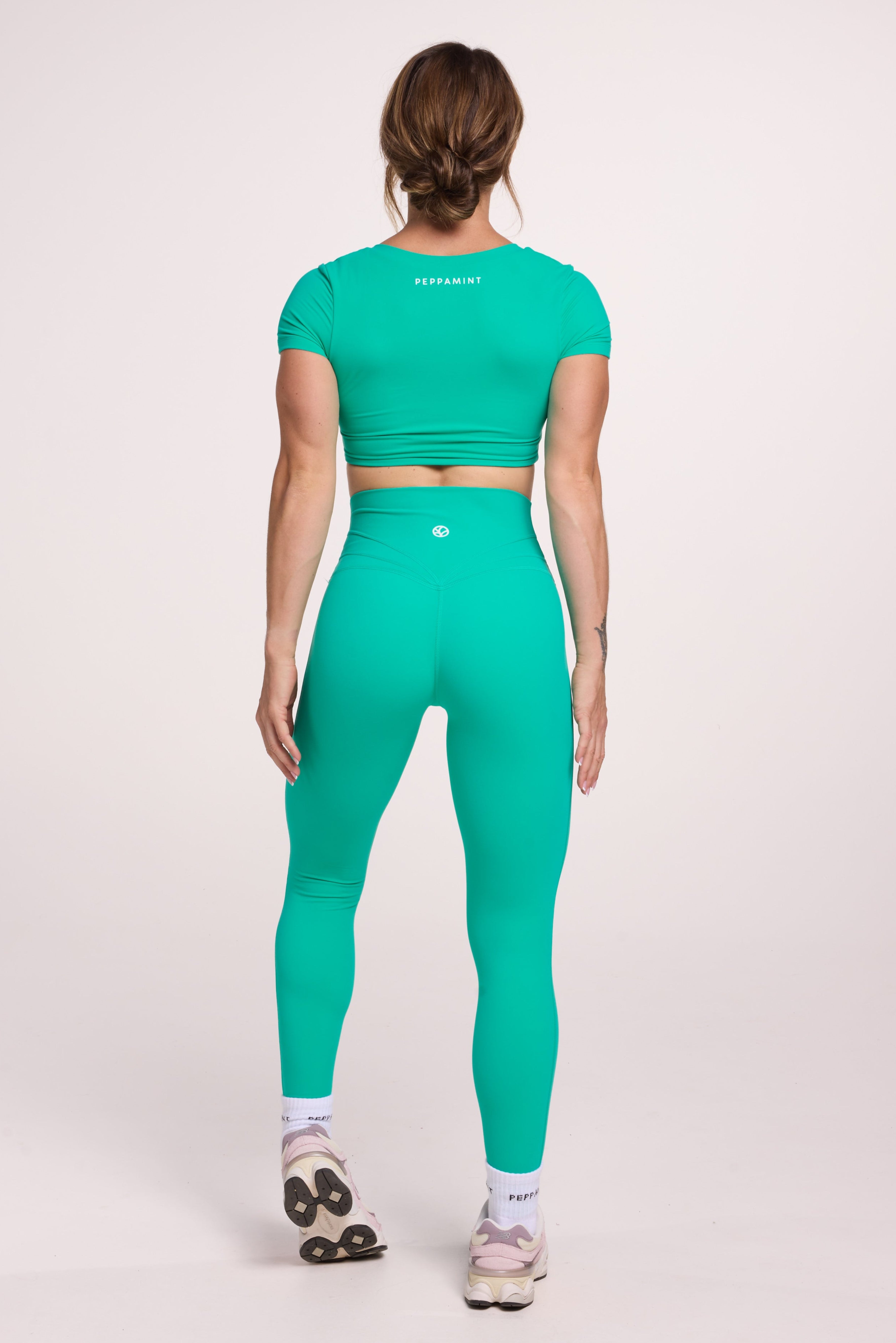 Buttery soft high waisted women's gym tights with curved back seam stitched detailing for a butt shaping effect, and no front rise seam paired with an V neck women's crop t-shirt with a supportive elasticated hem and triple layered fabric with removable pads for extra support in cyan green