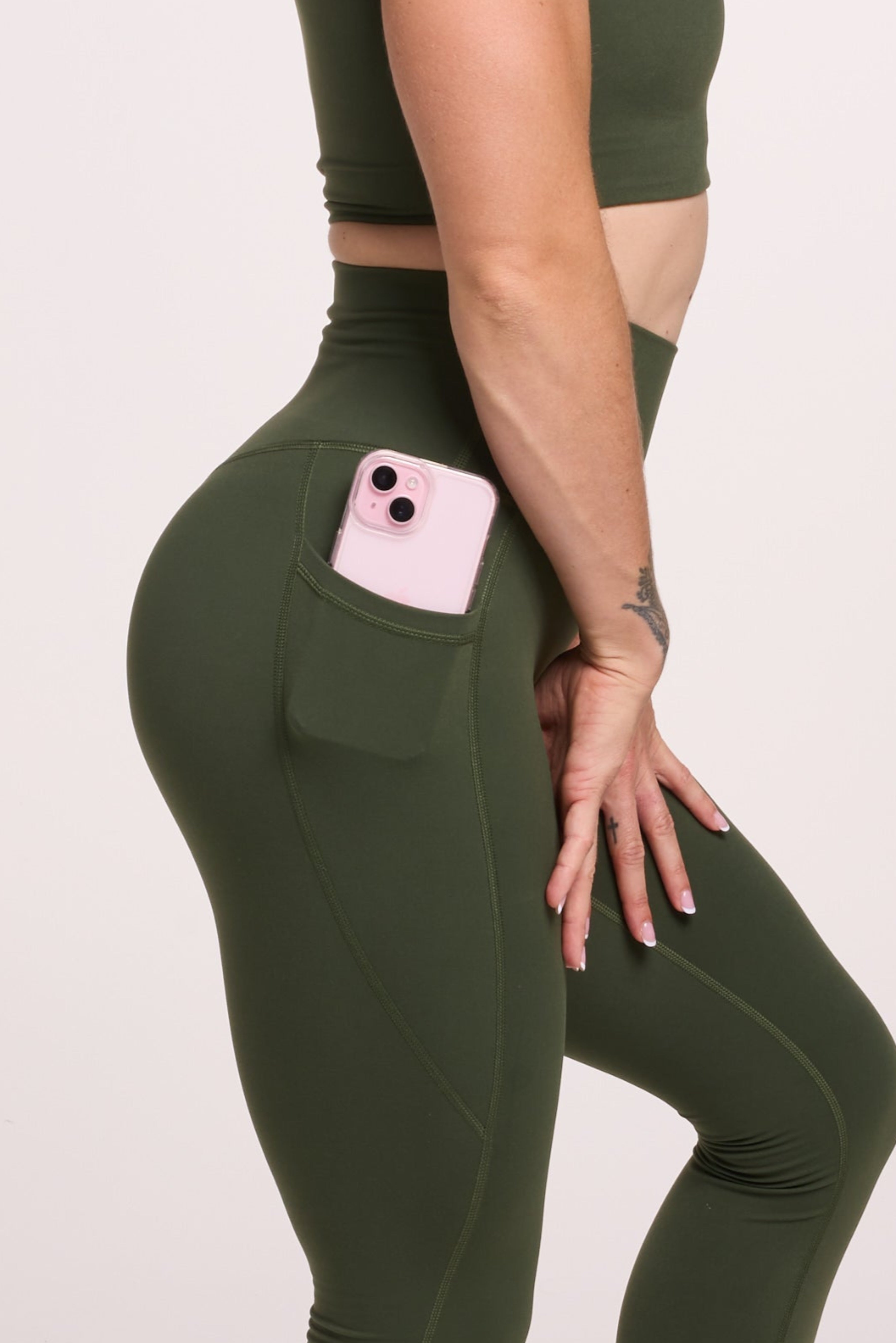 Buttery soft high waisted women's gym tights with practical pockets,  sweetheart back seams for an upper glute shaping effect, and no front rise seam, paired with a V neck women's crop t-shirt with a supportive elasticated hem and triple layered fabric with removable pads for extra support in forest green