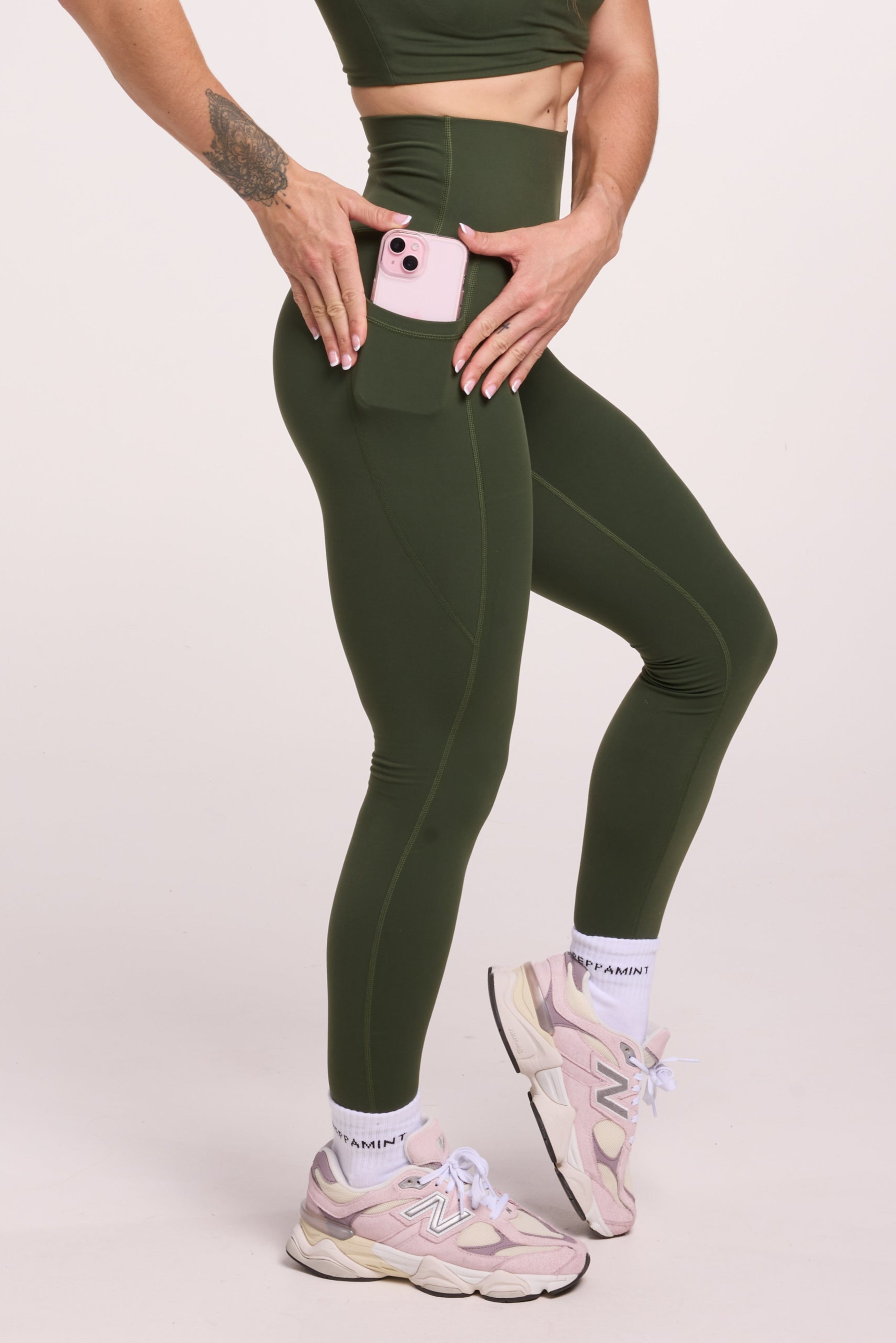 Buttery soft high waisted women's gym tights with practical pockets,  sweetheart back seams for an upper glute shaping effect, and no front rise seam, paired with a V neck women's crop t-shirt with a supportive elasticated hem and triple layered fabric with removable pads for extra support in forest green