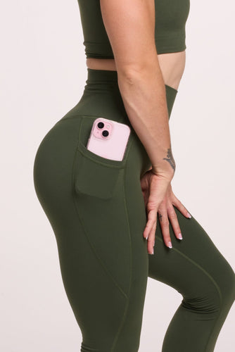 Buttery soft high waisted women's gym tights with practical pockets,  sweetheart back seams for an upper glute shaping effect, and no front rise seam, paired with a V neck women's crop t-shirt with a supportive elasticated hem and triple layered fabric with removable pads for extra support in forest green