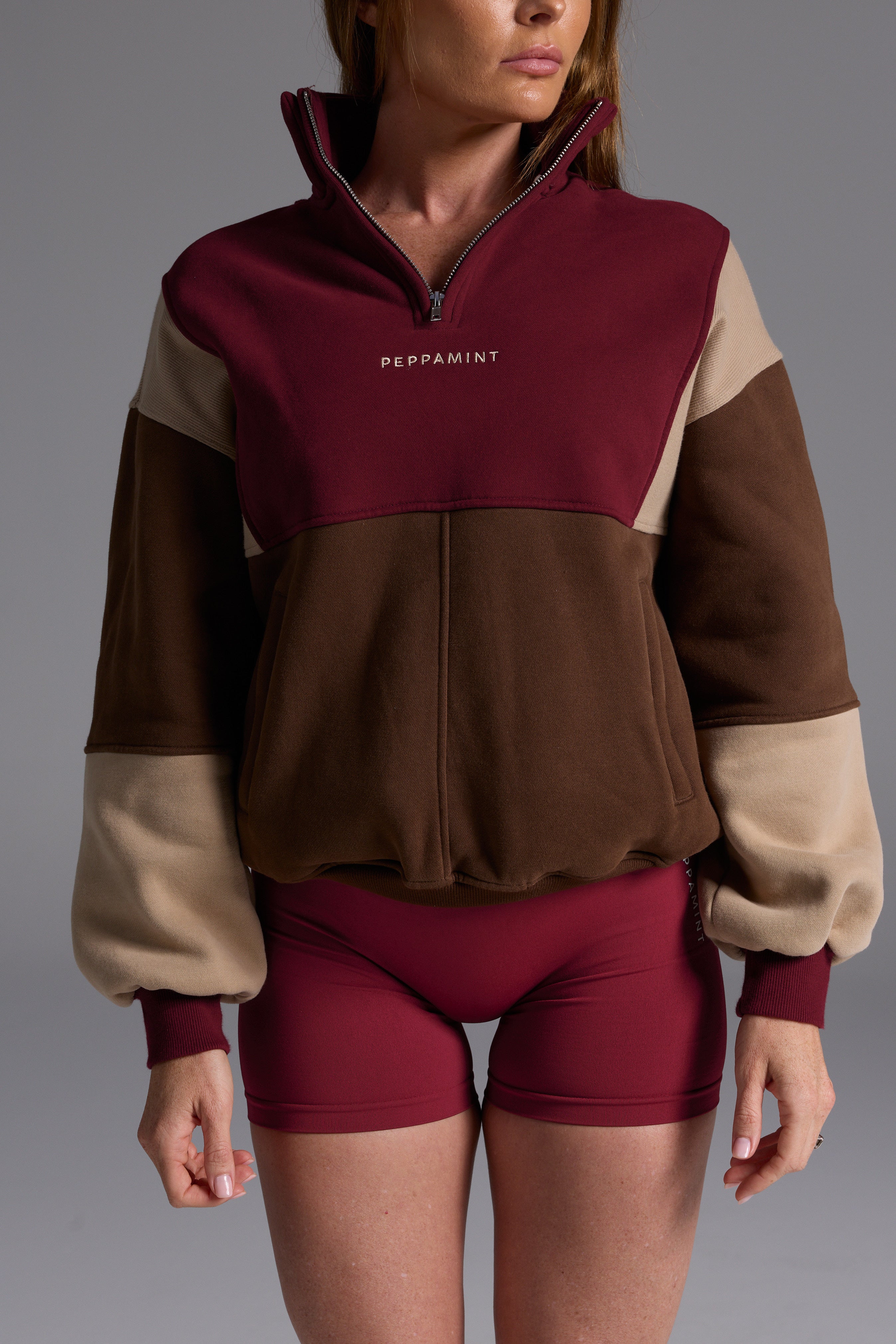 1/4 zip fleece jumper with double collar, ribbed stretchy fabric panel inserts, and two convenient zip pockets in a wine, chocolate and beige colour block design.