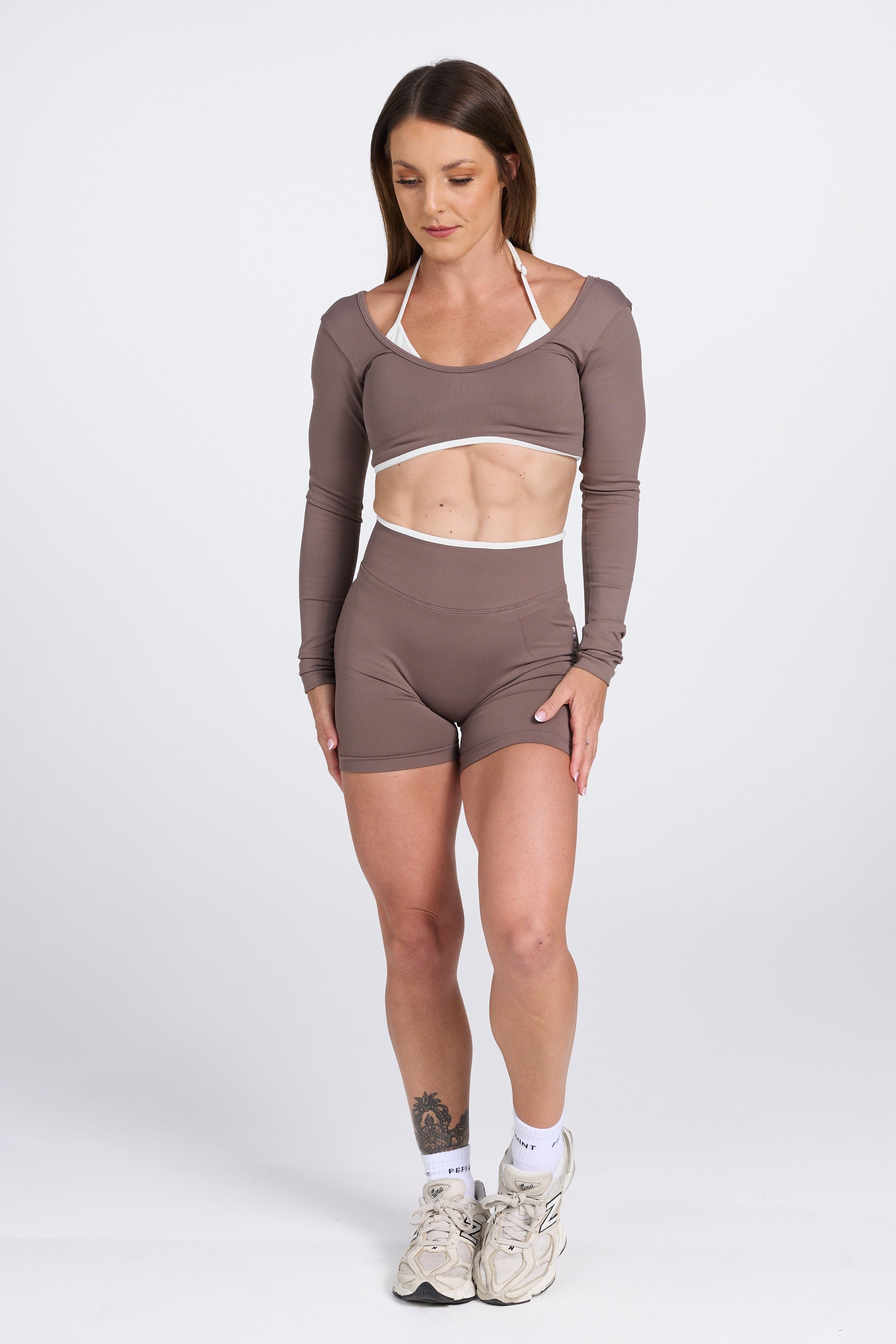 Long sleeve seamless crop top, with built in white contrasting bra, luxe white trim, and adjustable halter strap, with high waisted booty sculpting gym shorts in Mocha.