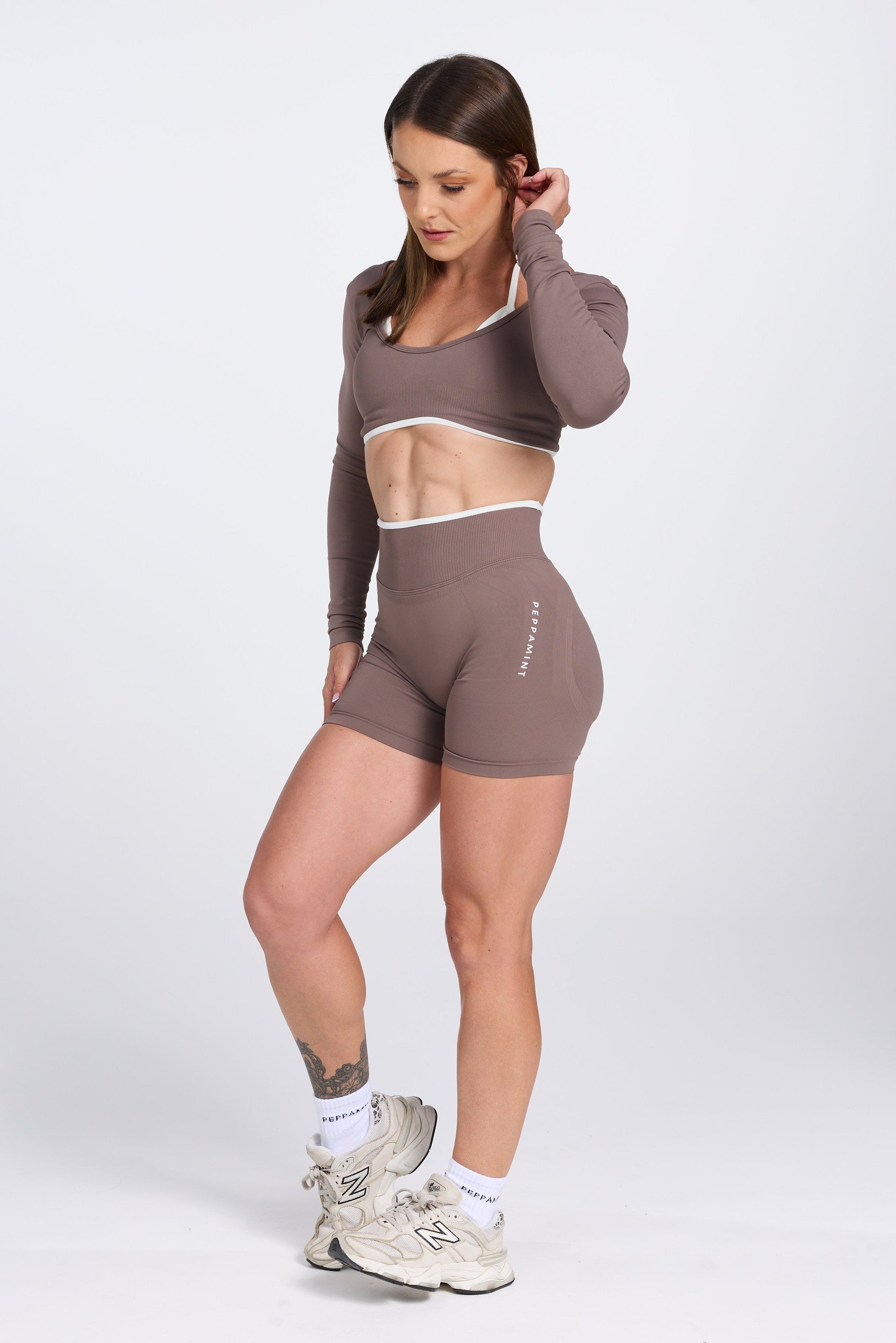 Long sleeve seamless crop top, with built in white contrasting bra, luxe white trim, and adjustable halter strap, with high waisted booty sculpting gym shorts in Mocha.