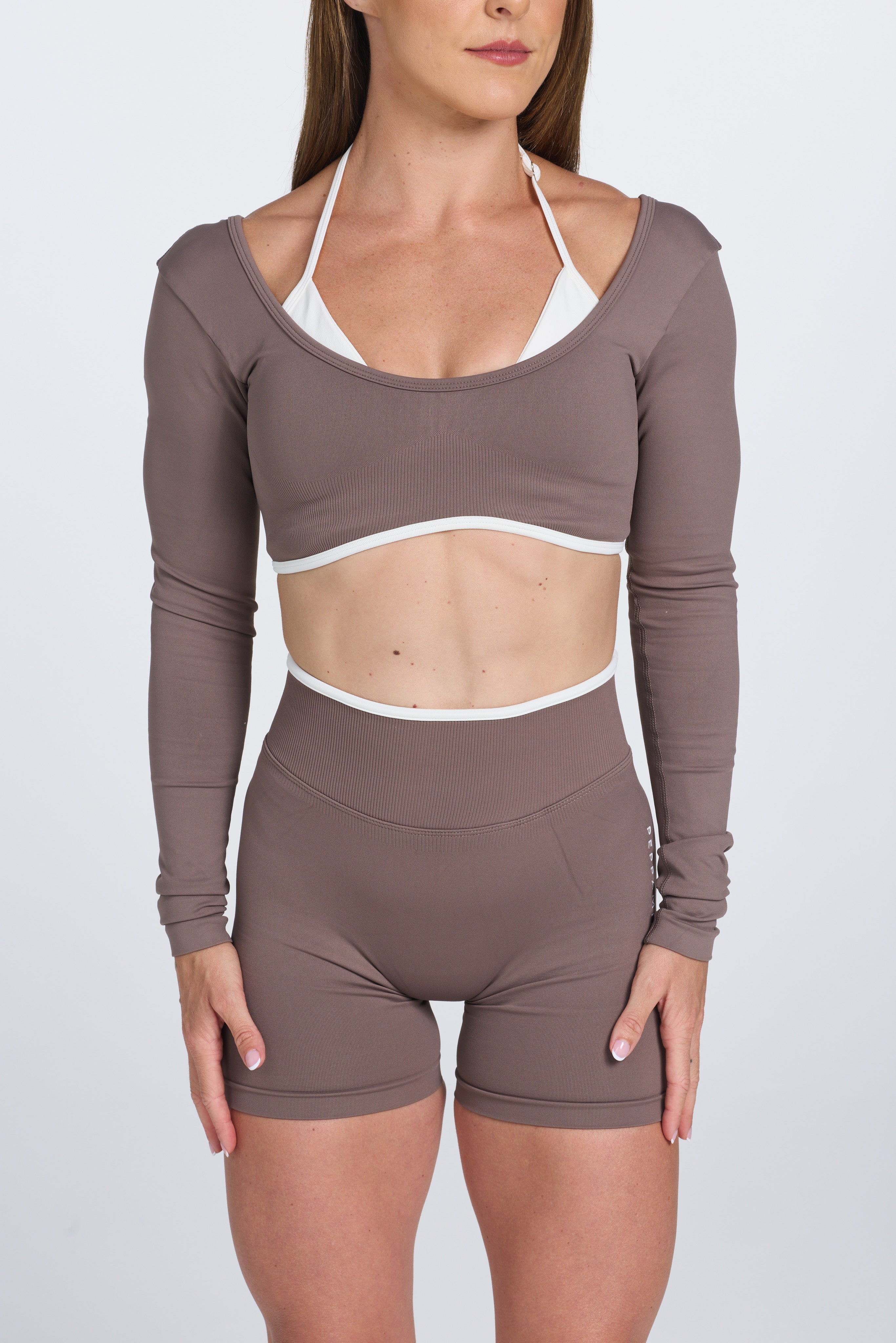 Long sleeve seamless crop top, with built in white contrasting bra, luxe white trim, and adjustable halter strap, with high waisted booty sculpting gym shorts in Mocha.