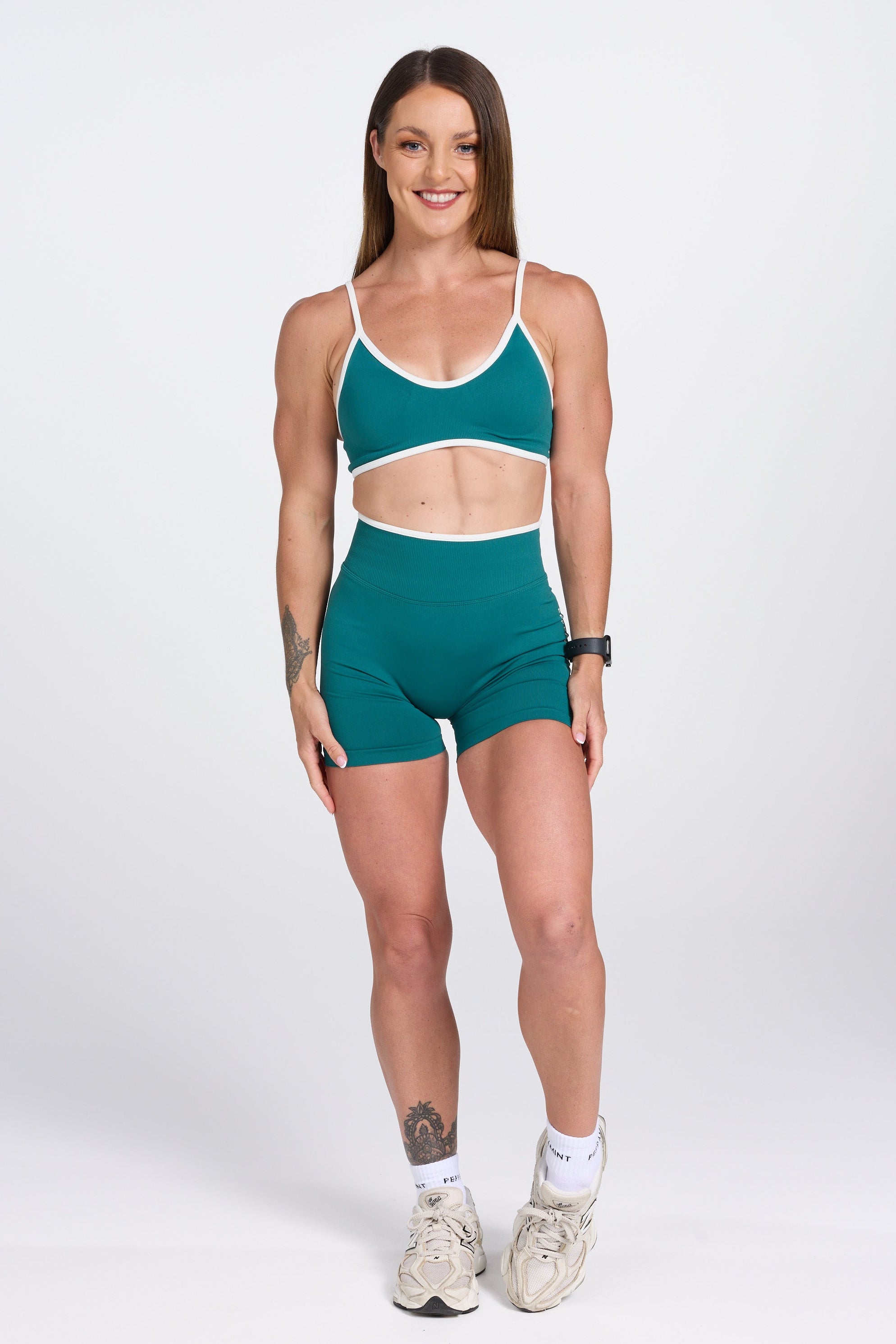 Seamless gym bra, with luxe white trim and adjustable back straps in teal colour.