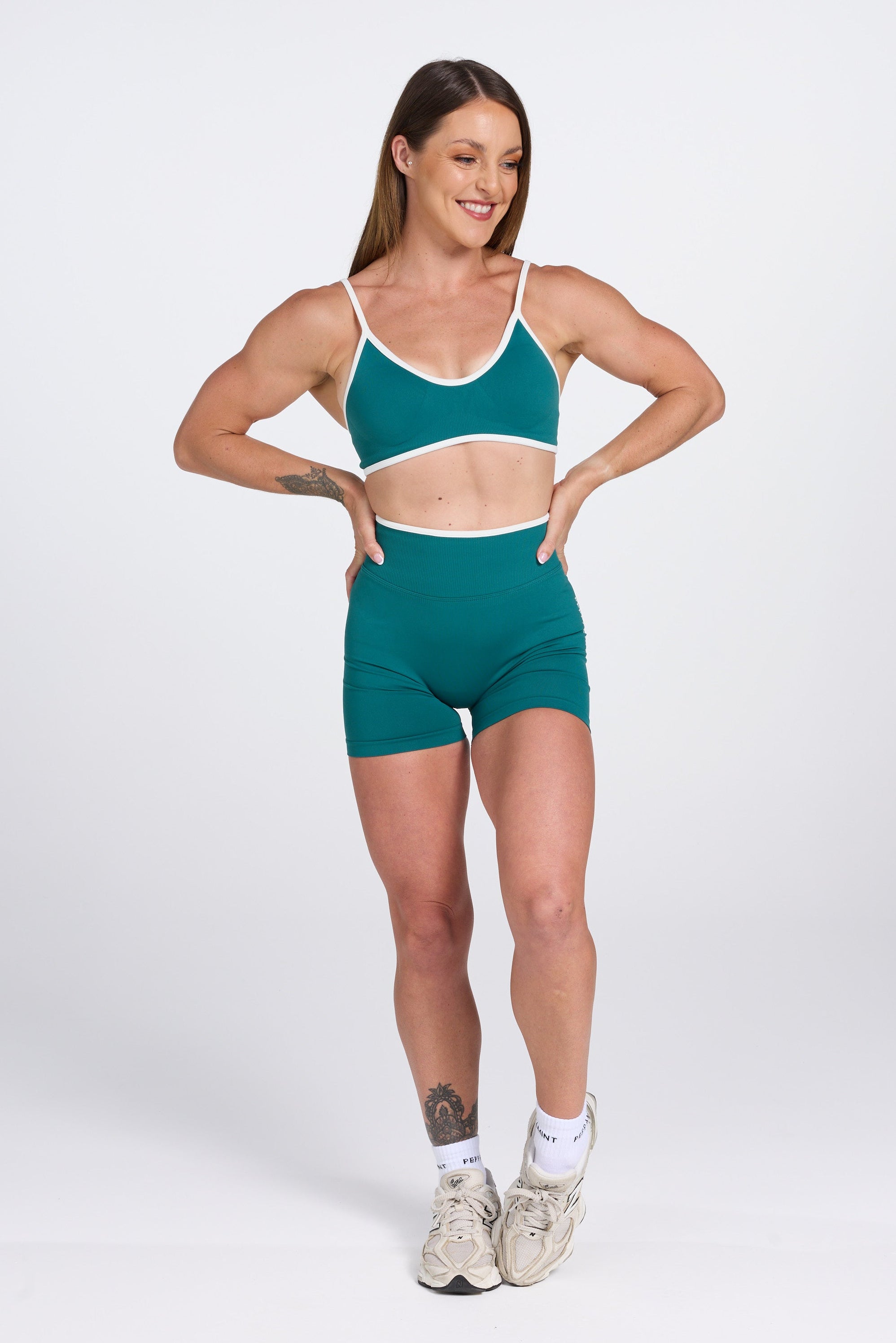 Seamless gym bra, with luxe white trim and adjustable back straps in teal colour.