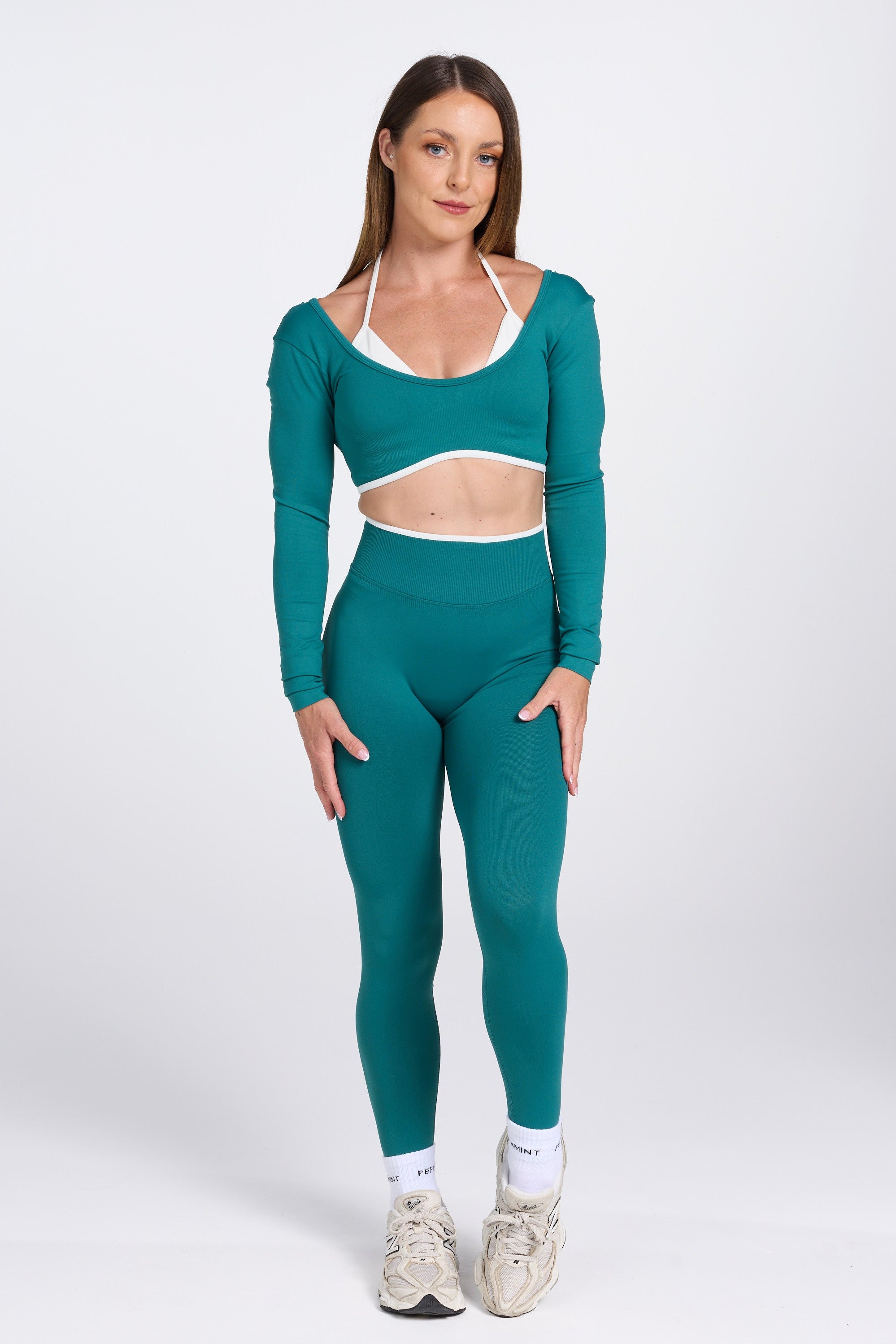 Long sleeve seamless crop top, with built in white contrasting bra, luxe white trim, and adjustable halter strap in teal colour.