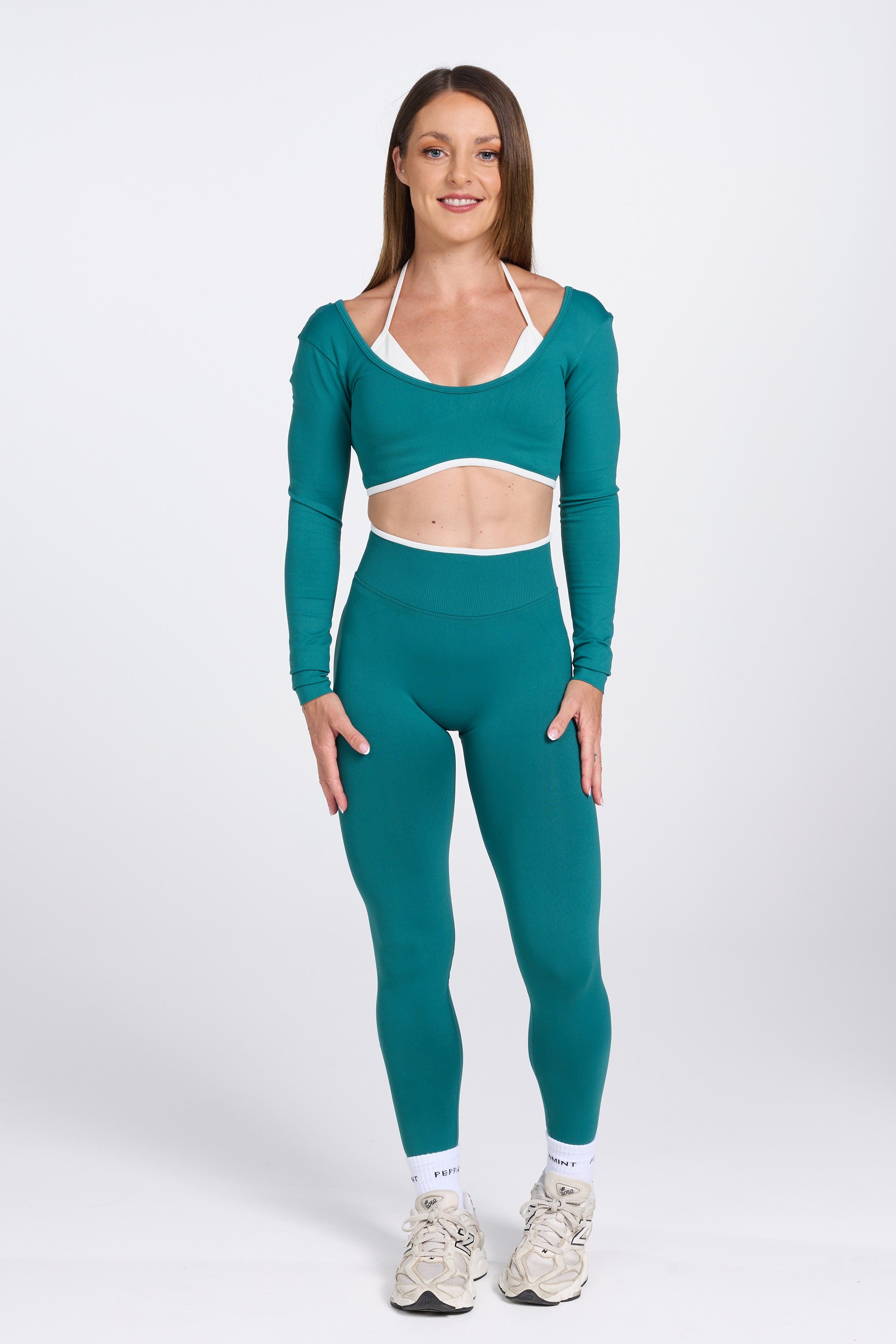 Long sleeve seamless crop top, with built in white contrasting bra, luxe white trim, and adjustable halter strap in teal colour.