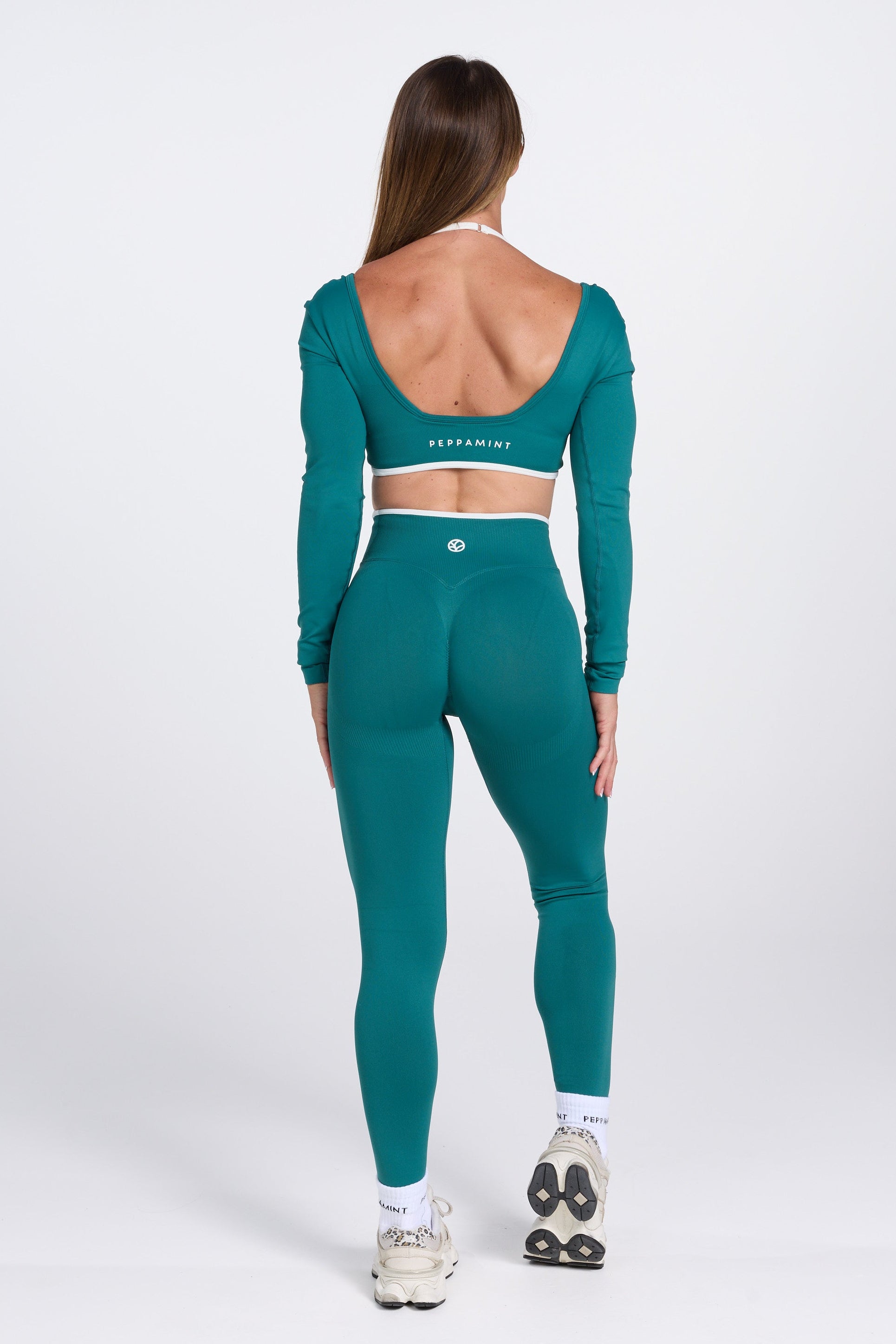 Long sleeve seamless crop top, with built in white contrasting bra, luxe white trim, and adjustable halter strap in teal colour.