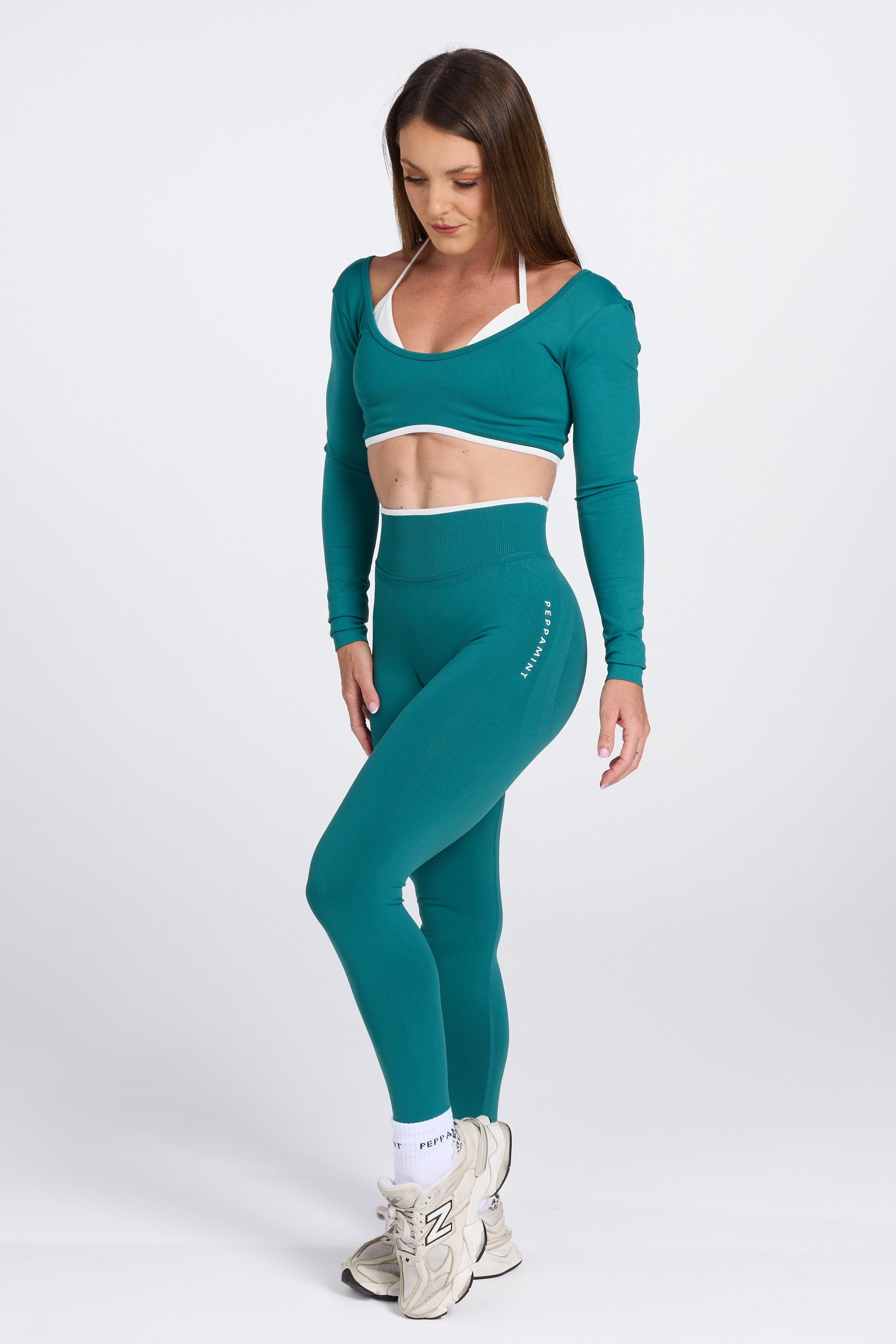 Long sleeve seamless crop top, with built in white contrasting bra, luxe white trim, and adjustable halter strap in teal colour.