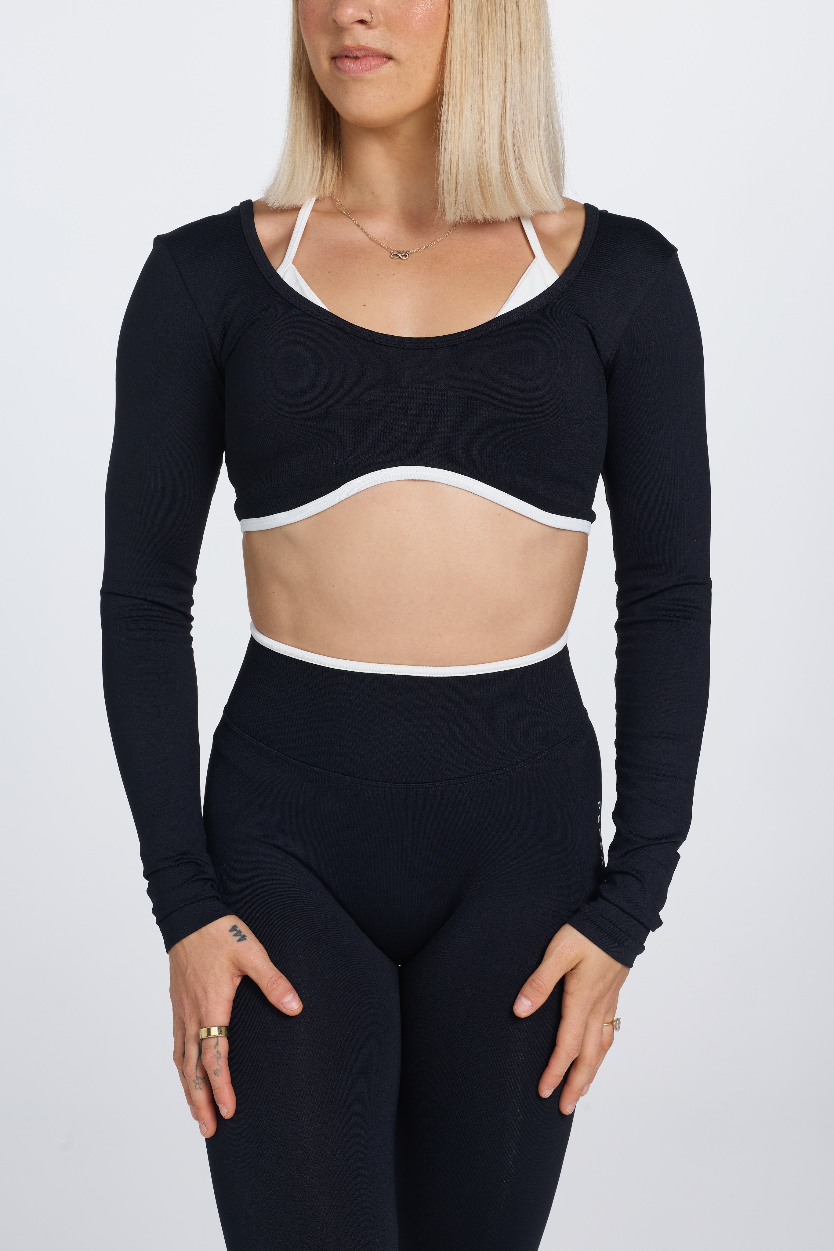 Long sleeve seamless crop top, with built in white contrasting bra, luxe white trim, and adjustable halter strap in black colour.