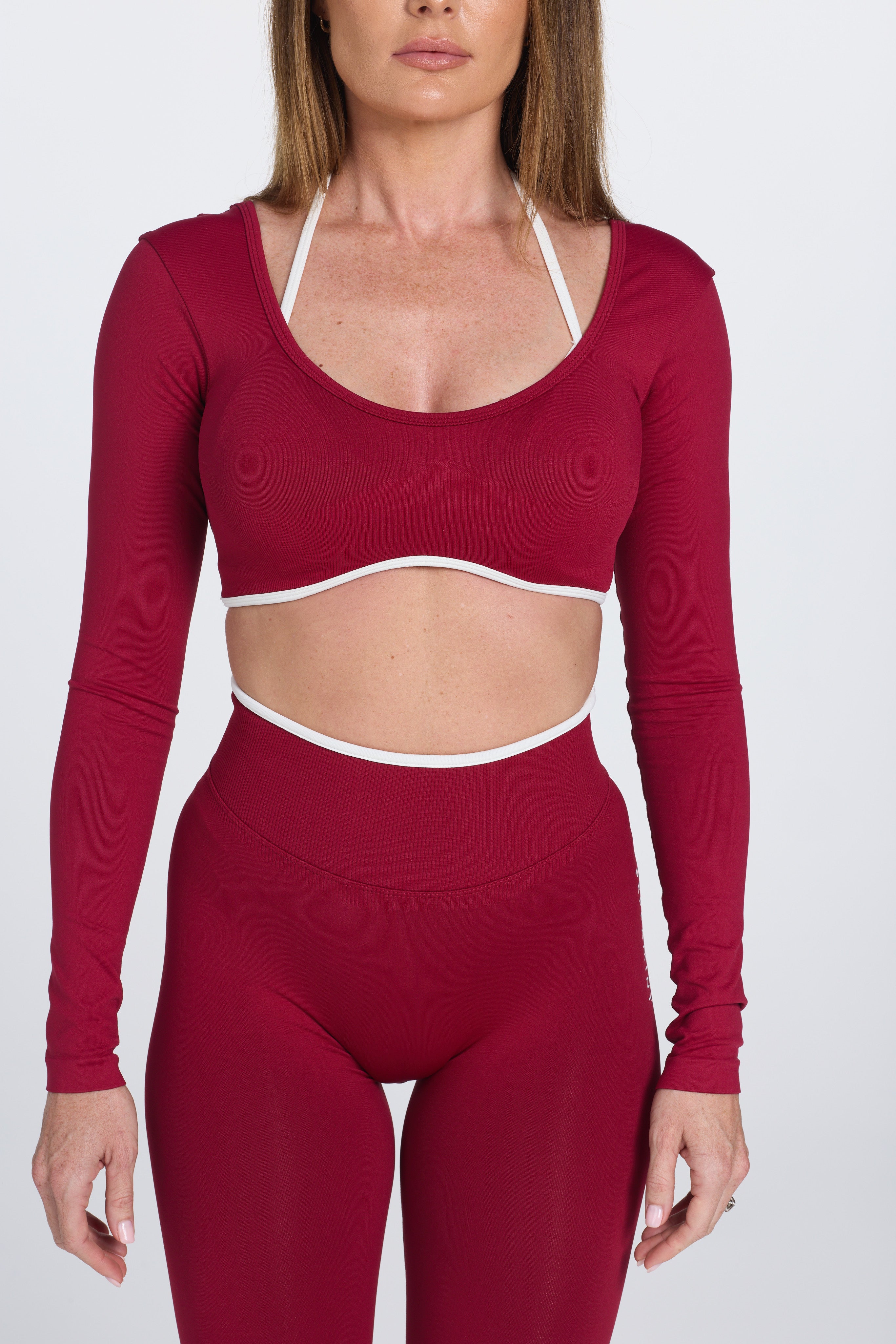 Long sleeve seamless crop top, with built in white contrasting bra, luxe white trim, and adjustable halter strap in wine colour.