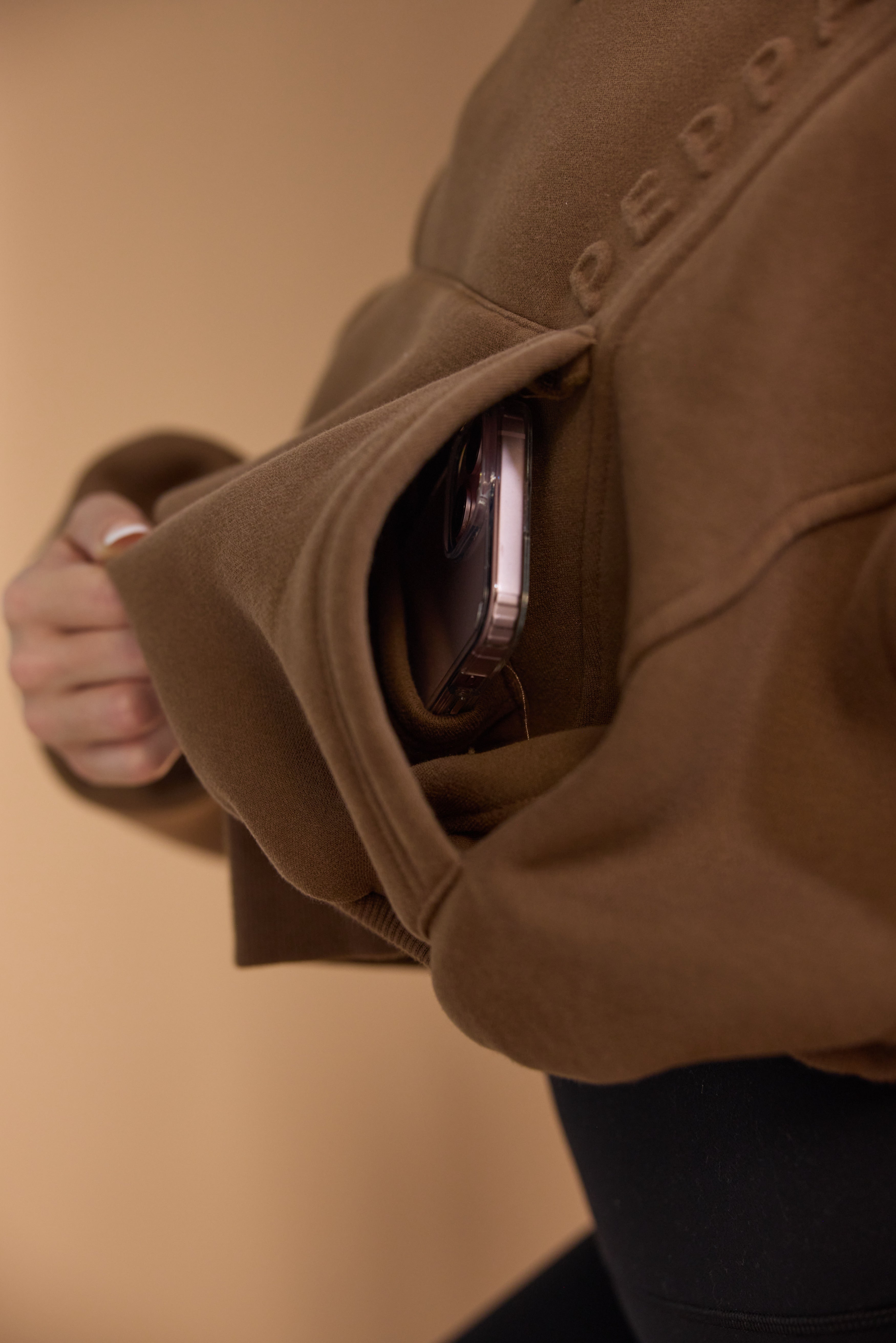 Oversize batwing hoodie, hip length, with slouchy oversized sleeves, piped seams, iconic ribbed panels and a kangaroo pocket with a hidden phone pocket inside in chocolate brown colour