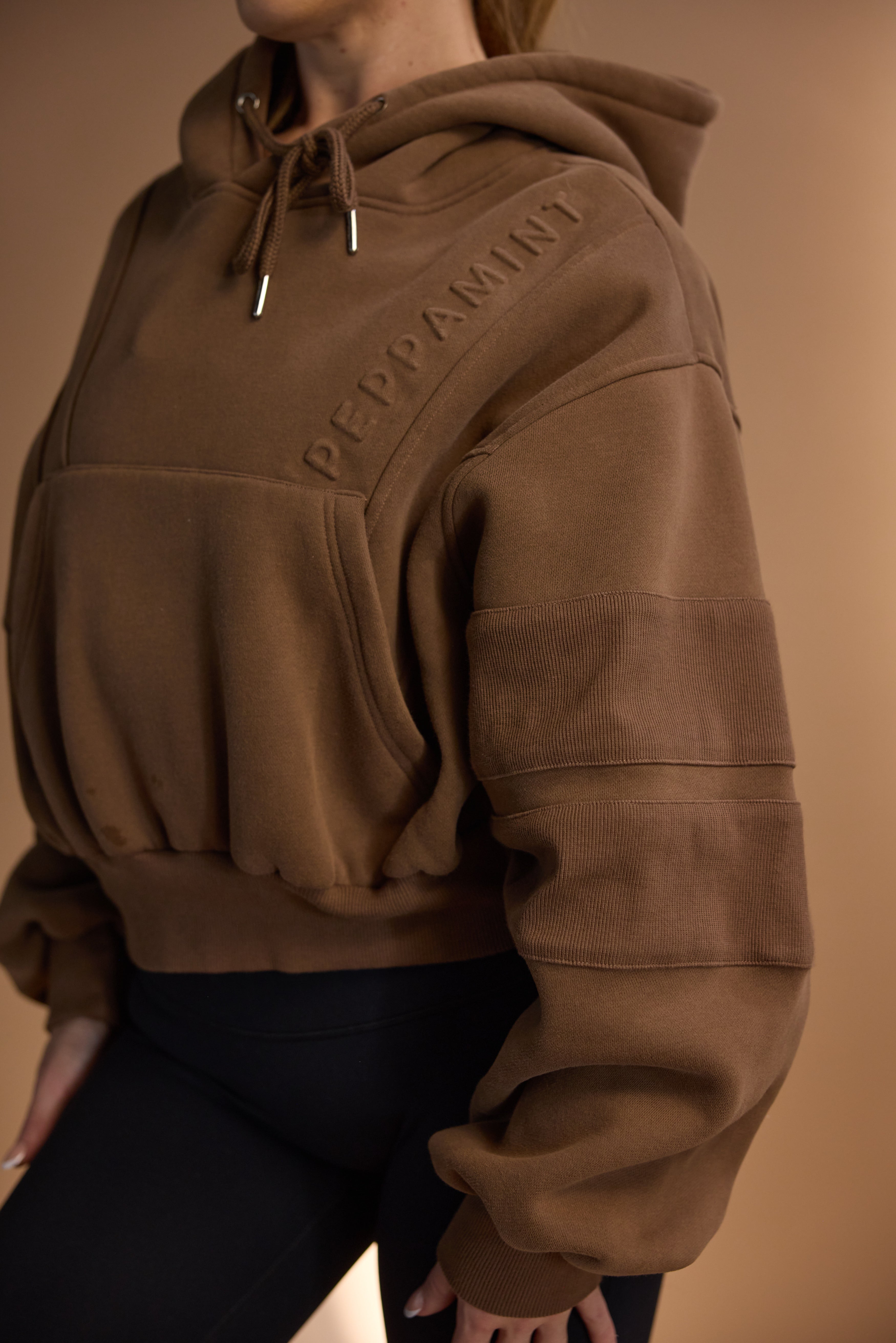 Oversize batwing hoodie, hip length, with slouchy oversized sleeves, piped seams, iconic ribbed panels and a kangaroo pocket with a hidden phone pocket inside in chocolate brown colour