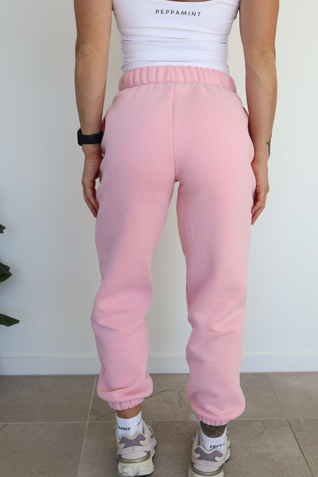 Fleece lined joggers in baby pink with elasticated waistband, drawstring, two side pockets and a subtle embossed logo icon on left pocket