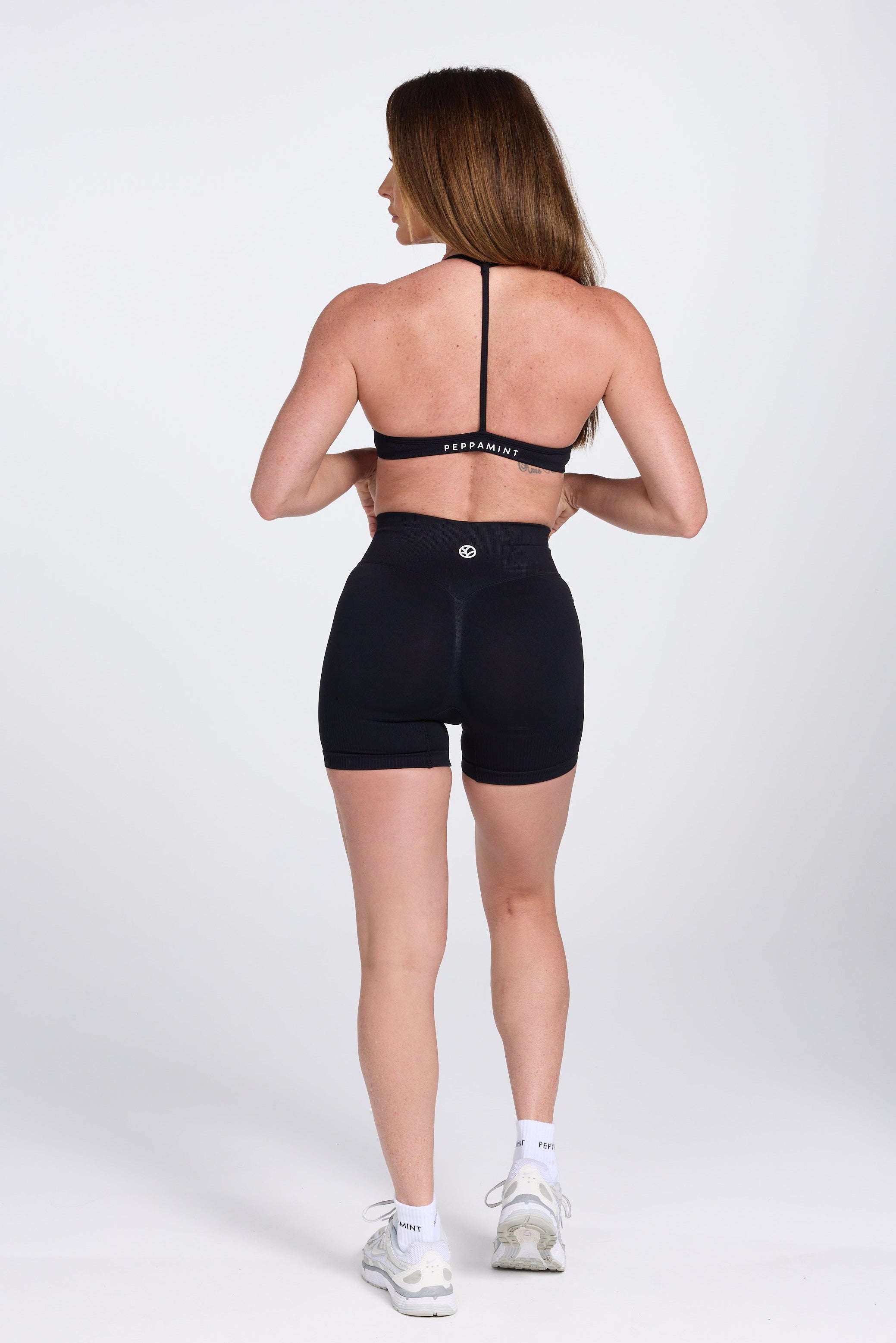 Seamless women’s gym bra with an ultra thin racerback strap design, with white PEPPAMINT branding on the back strap paired with high waisted gym shorts with booty contouring panels, invisible scrunch technology, sweetheart shaped back seams and thick supportive fabric iblack