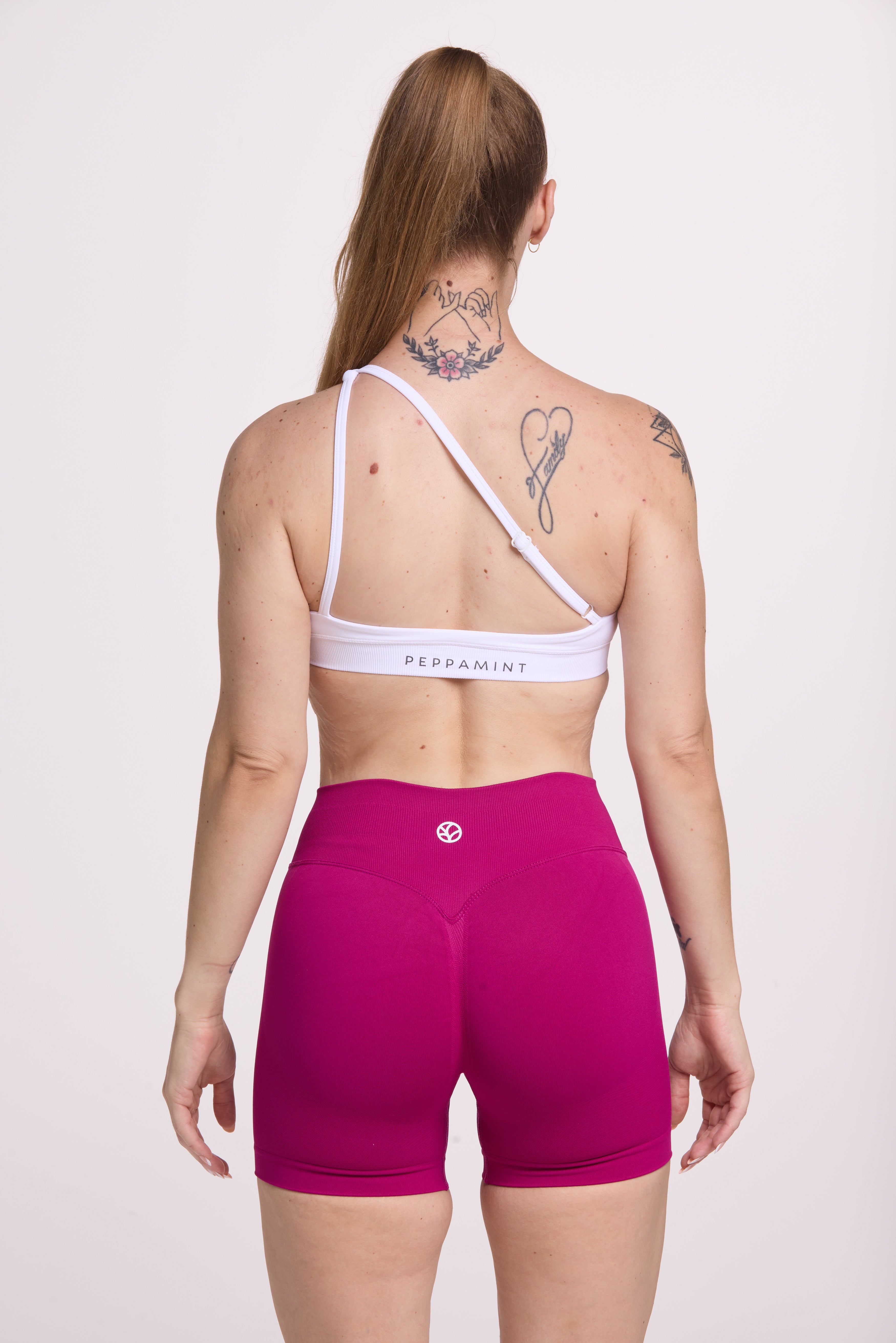 Front cross over strap activewear bra in seamless fabric with adjustable back straps, and ribbed supportive underbust band in white and seamless gym tights with booty contouring panels, invisible scrunch technology, sweetheart shaped back seams and thick supportive fabric in magenta pink