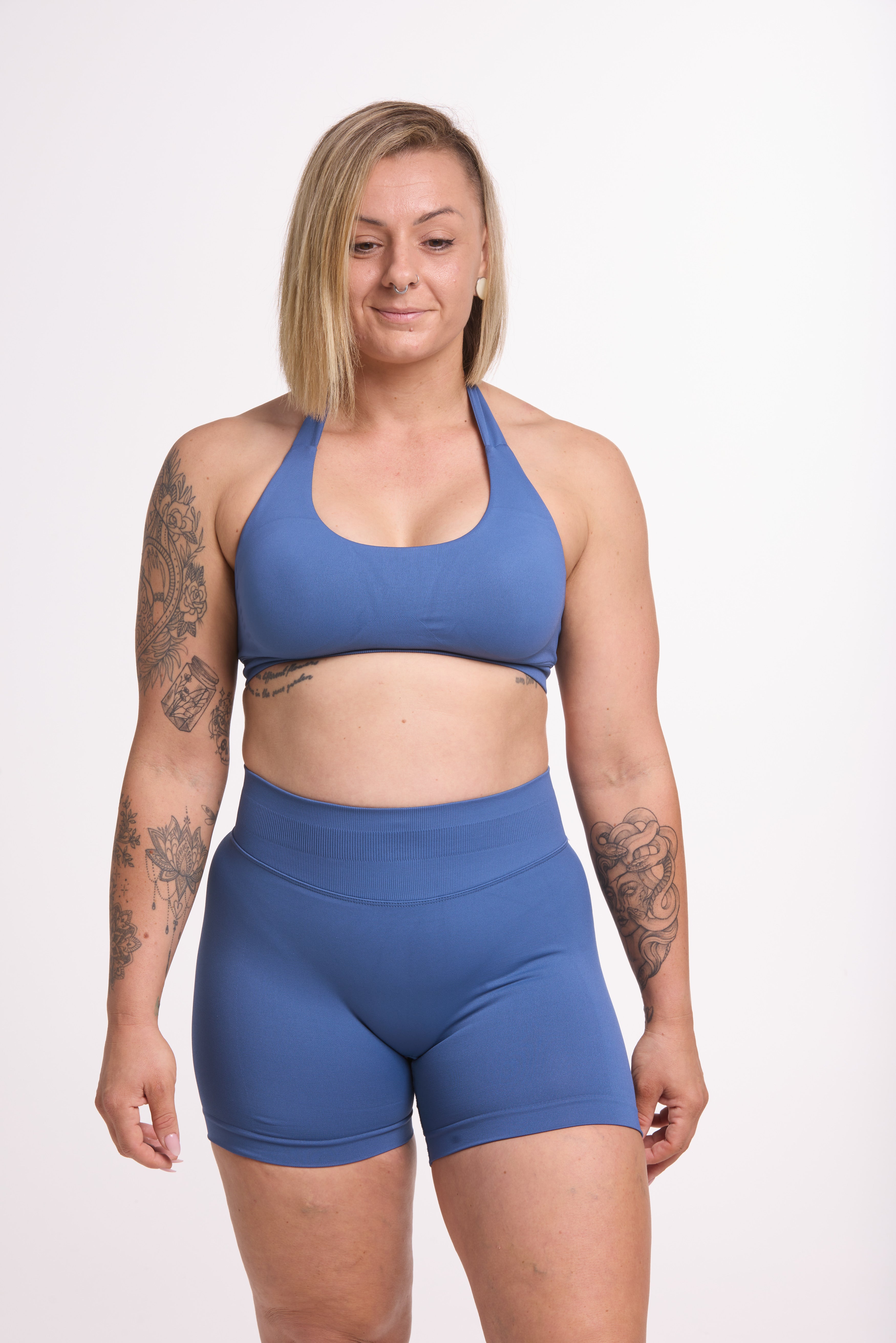 Seamless halter bra with a thick supportive fabric blend and a branded back strap, with a ribbed elastic hem and seamless shorts with booty contouring panels, invisible scrunch technology, a sweetheart shaped back seam, and a thick supportive waistband in grey blue colour