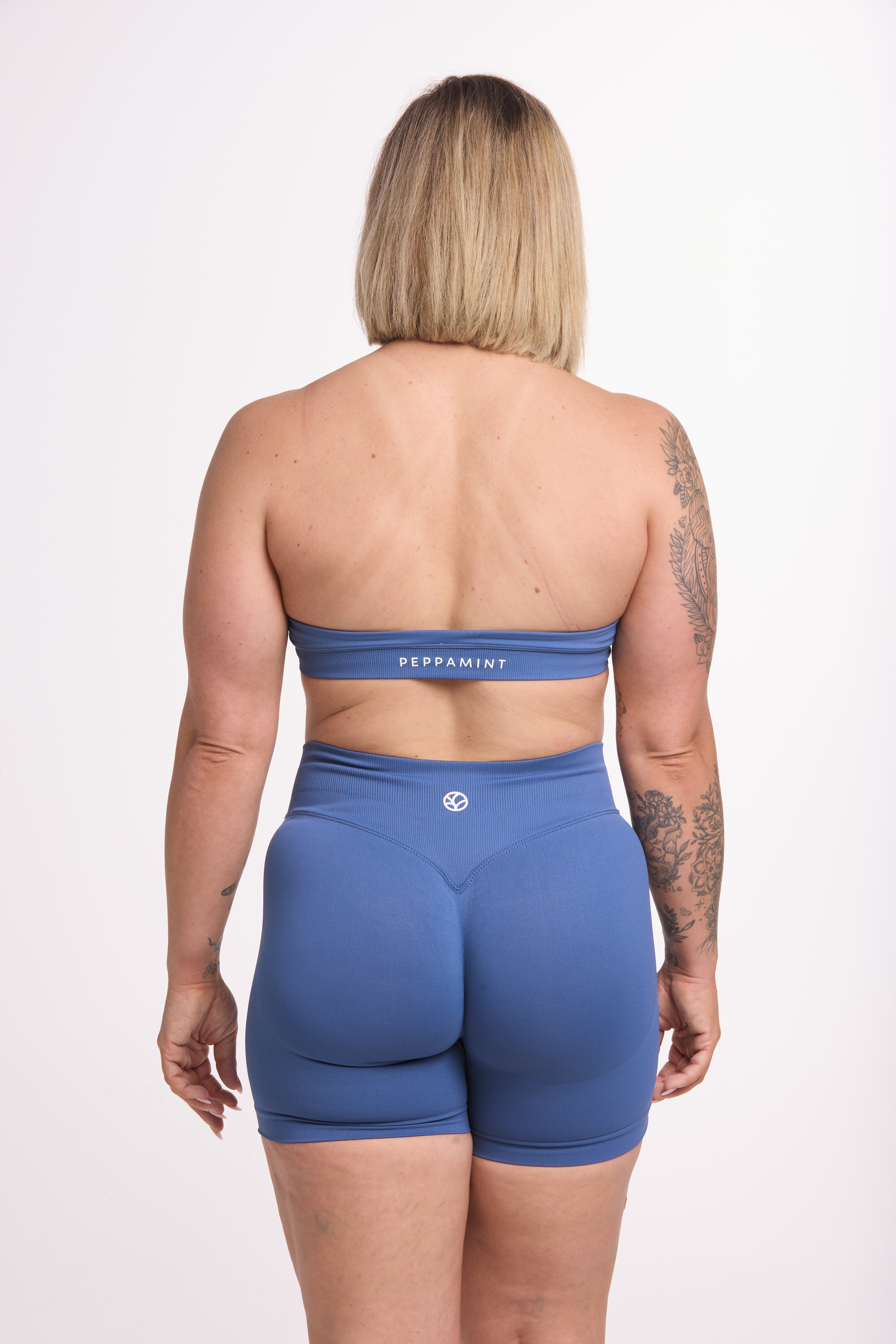 Seamless halter bra with a thick supportive fabric blend and a branded back strap, with a ribbed elastic hem and seamless shorts with booty contouring panels, invisible scrunch technology, a sweetheart shaped back seam, and a thick supportive waistband in grey blue colour