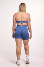 Load image into Gallery viewer, Seamless halter bra with a thick supportive fabric blend and a branded back strap, with a ribbed elastic hem and seamless shorts with booty contouring panels, invisible scrunch technology, a sweetheart shaped back seam, and a thick supportive waistband in grey blue colour
