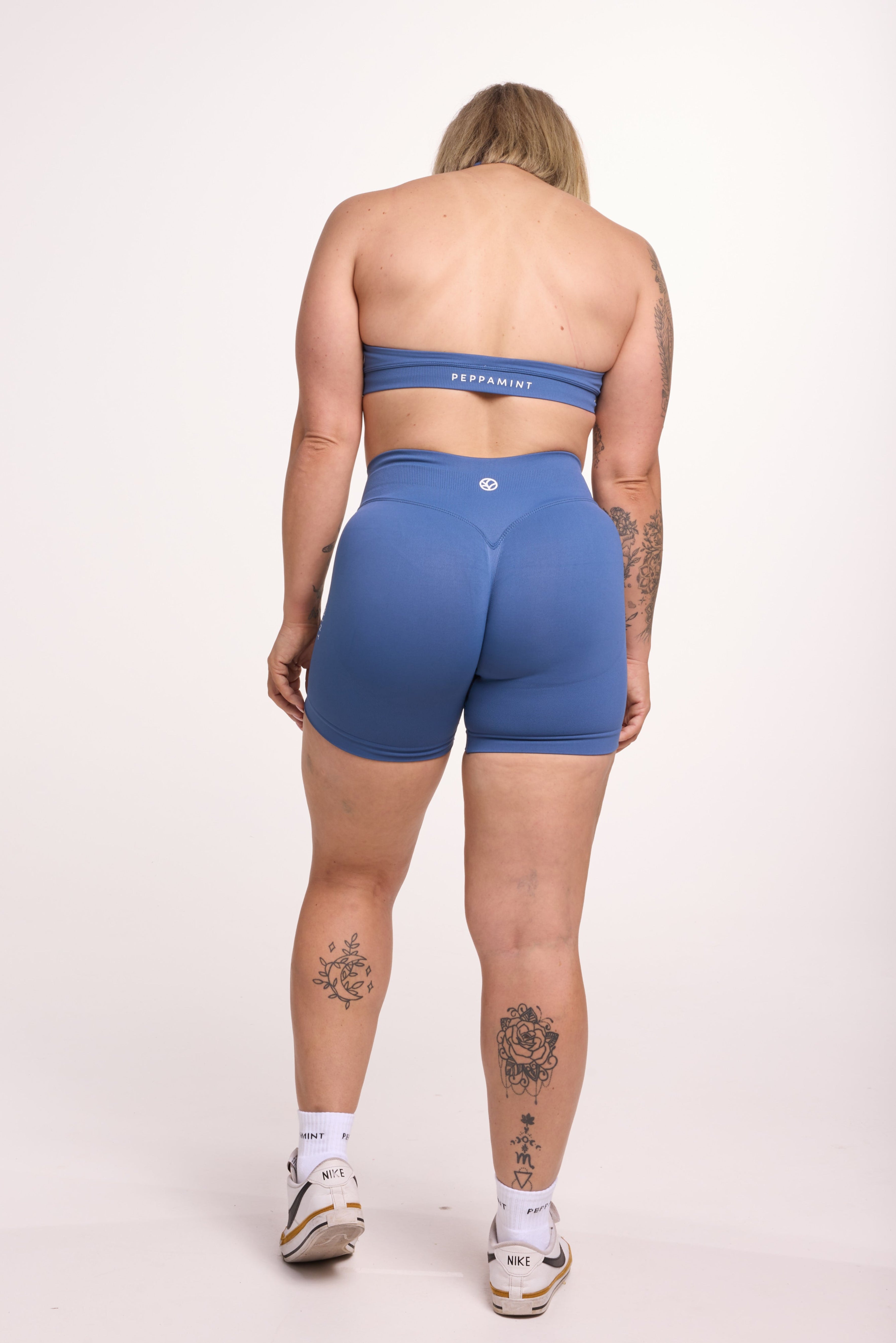 Seamless halter bra with a thick supportive fabric blend and a branded back strap, with a ribbed elastic hem and seamless shorts with booty contouring panels, invisible scrunch technology, a sweetheart shaped back seam, and a thick supportive waistband in grey blue colour