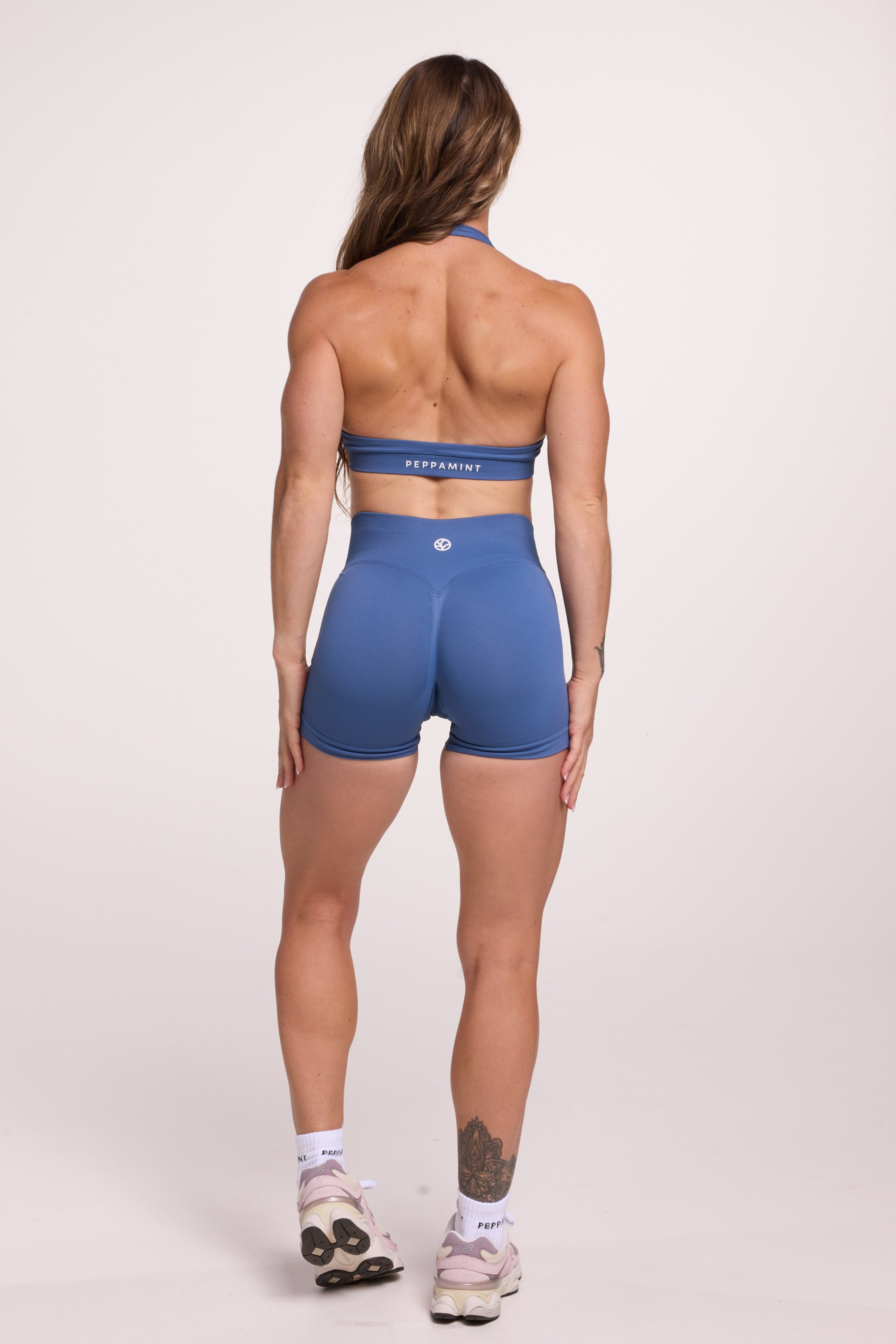 Seamless halter bra with a thick supportive fabric blend and a branded back strap, with a ribbed elastic hem and seamless shorts with booty contouring panels, invisible scrunch technology, a sweetheart shaped back seam, and a thick supportive waistband in grey blue colour