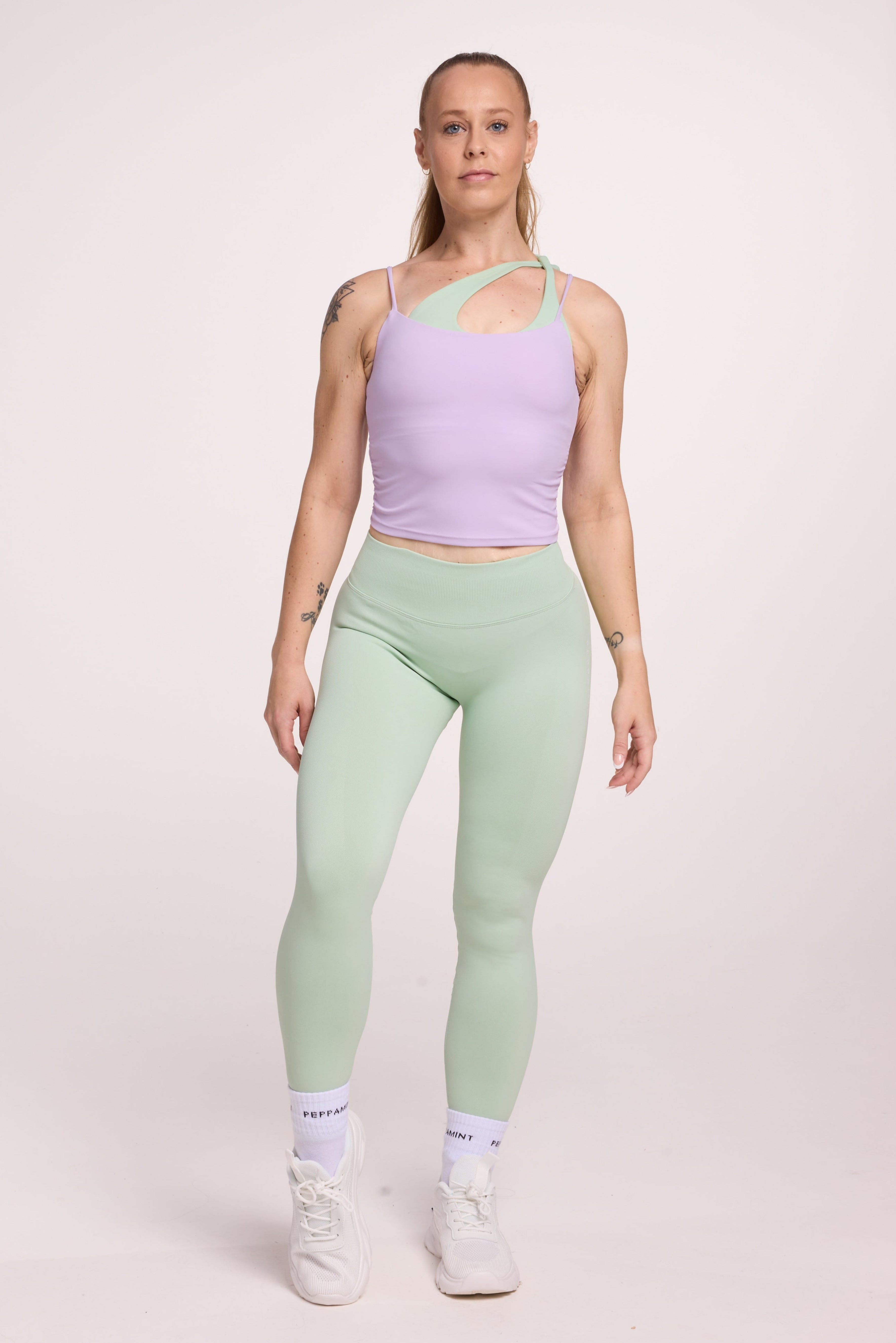 Buttery soft singlet with ruched side seams, spaghetti straps and built in shelf bra with removable pads in lavender with seamless gym tights with booty contouring panels, invisible scrunch technology, sweetheart shaped back seams and thick supportive fabric in mist green