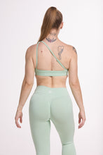 Load image into Gallery viewer, Front cross over strap activewear bra in seamless fabric with adjustable back straps, and ribbed supportive under bust band with seamless gym tights with booty contouring panels, invisible scrunch technology, sweetheart shaped back seams and thick supportive fabric in mist green

