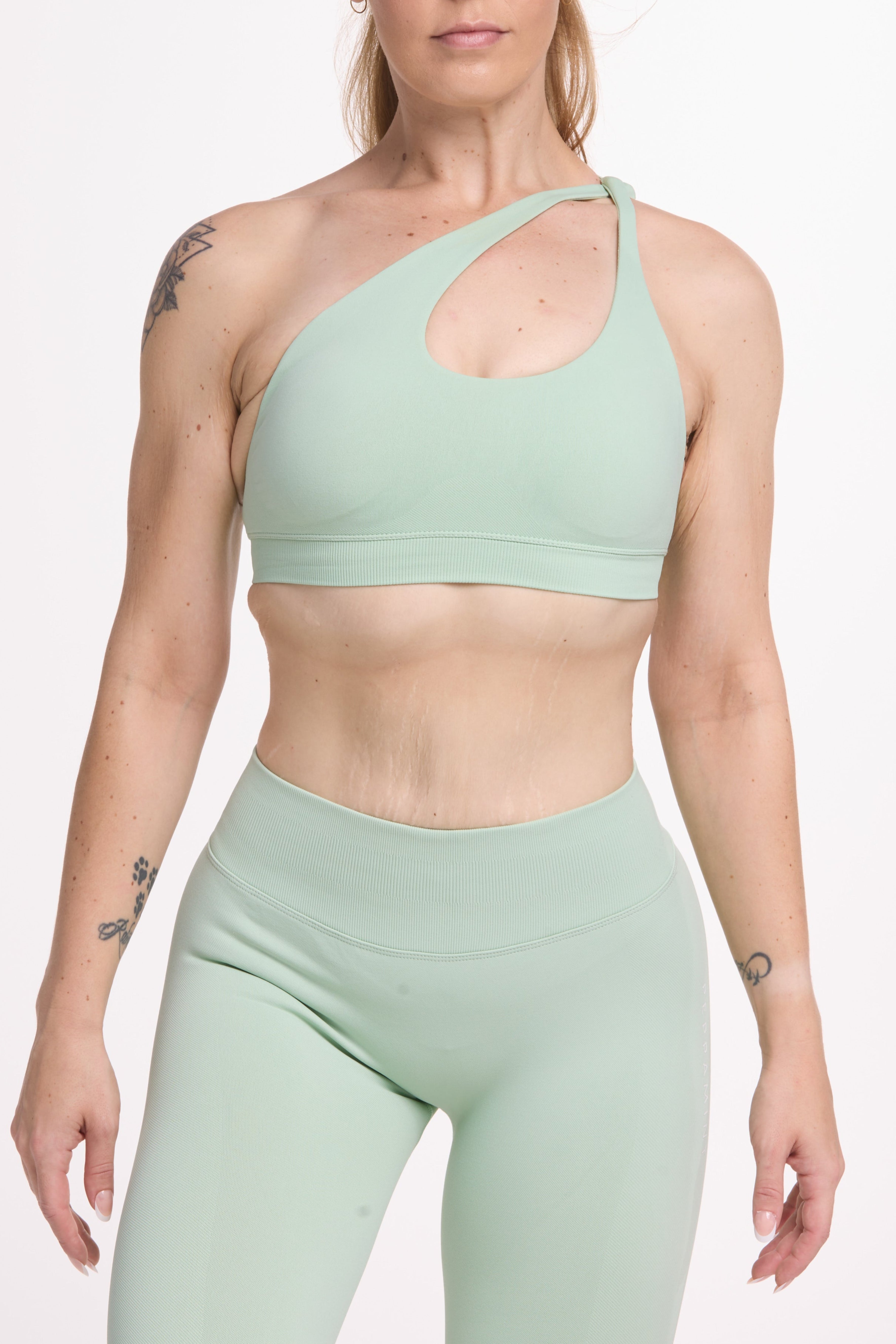 Front cross over strap activewear bra in seamless fabric with adjustable back straps, and ribbed supportive under bust band with seamless gym tights with booty contouring panels, invisible scrunch technology, sweetheart shaped back seams and thick supportive fabric in mist green