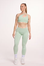 Load image into Gallery viewer, Front cross over strap activewear bra in seamless fabric with adjustable back straps, and ribbed supportive under bust band with seamless gym tights with booty contouring panels, invisible scrunch technology, sweetheart shaped back seams and thick supportive fabric in mist green

