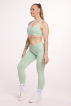 Load image into Gallery viewer, Front cross over strap activewear bra in seamless fabric with adjustable back straps, and ribbed supportive under bust band with seamless gym tights with booty contouring panels, invisible scrunch technology, sweetheart shaped back seams and thick supportive fabric in mist green
