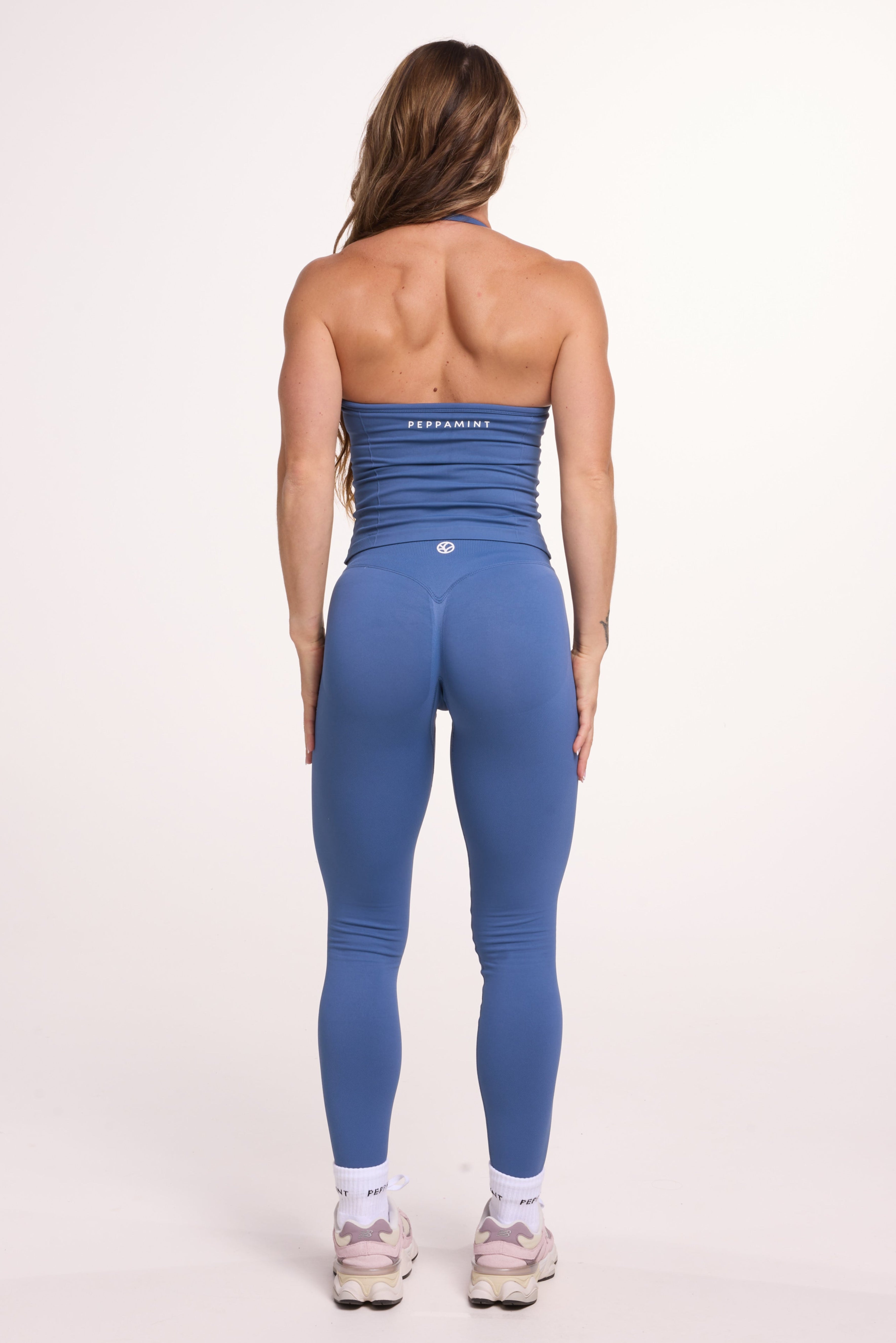 Halter neck tank top with breast contouring panels and a ruched front seam, a built in bra, and an open upper back design and seamless gym tights with booty contouring panels, invisible scrunch technology, sweetheart shaped back seams and thick supportive fabrics in grey blue colour 