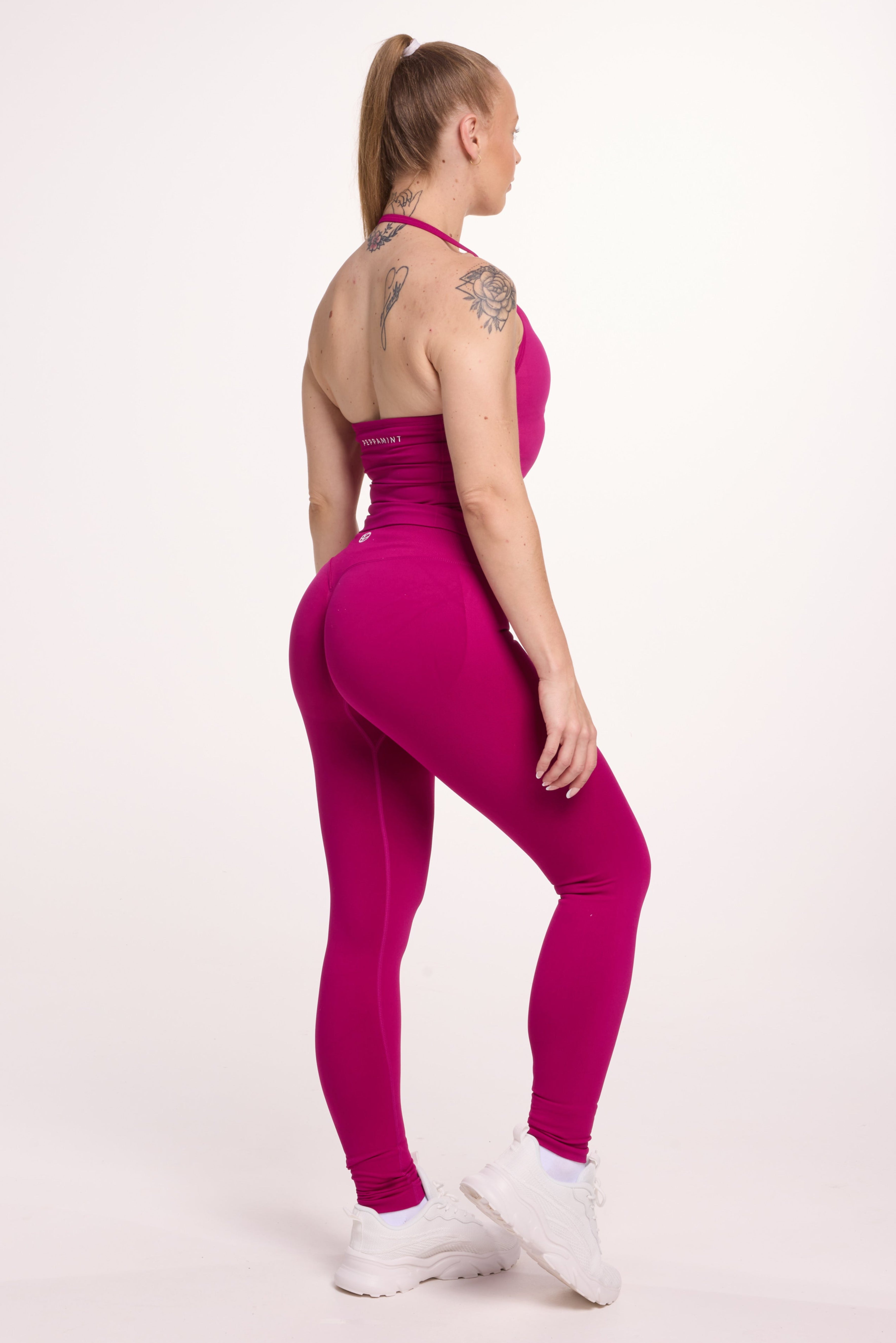Halter neck tank top with breast contouring panels and a ruched front seam, a built in bra, and an open upper back design and seamless gym tights with booty contouring panels, invisible scrunch technology, sweetheart shaped back seams and thick supportive fabrics in magenta