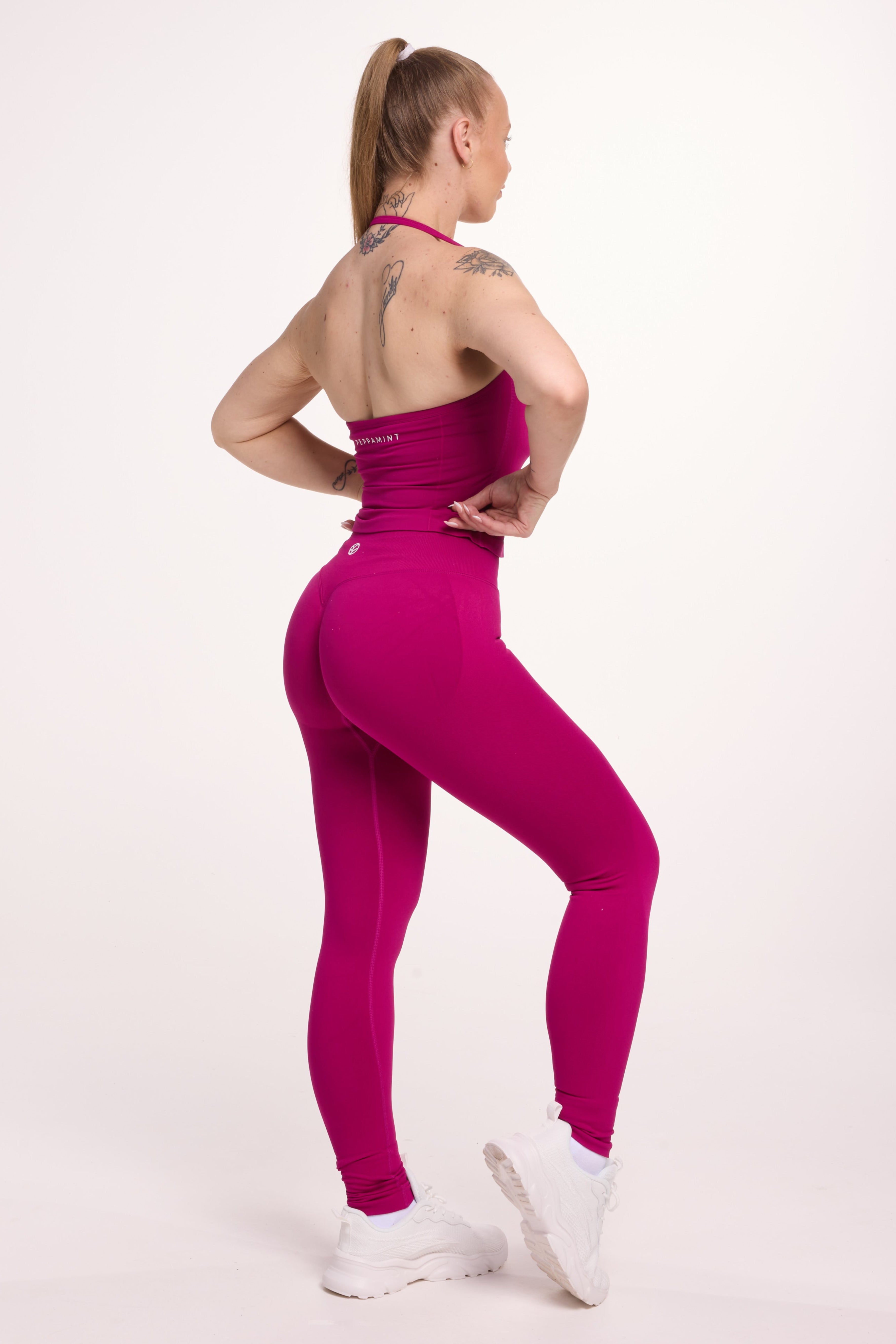 Halter neck tank top with breast contouring panels and a ruched front seam, a built in bra, and an open upper back design and seamless gym tights with booty contouring panels, invisible scrunch technology, sweetheart shaped back seams and thick supportive fabrics in magenta