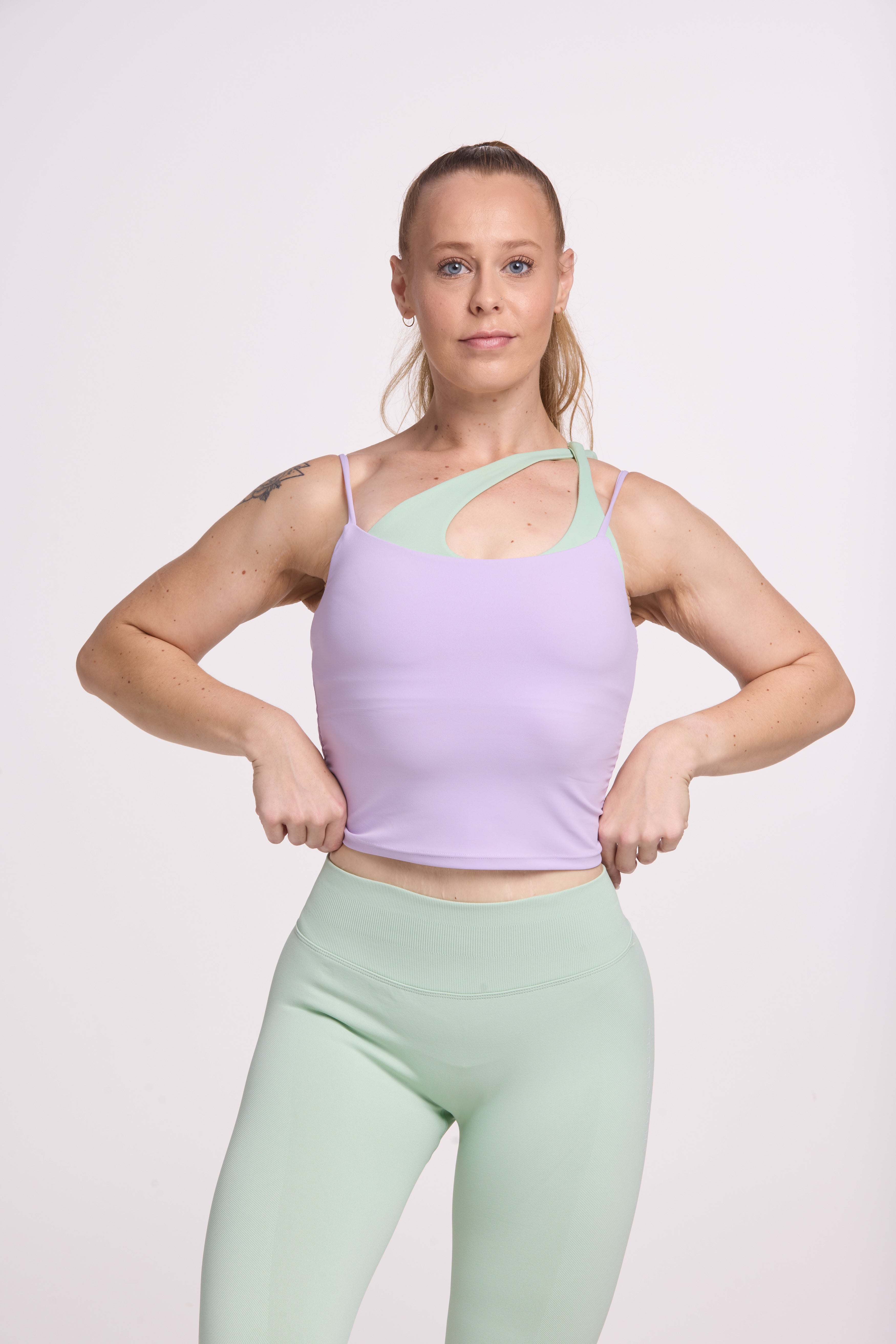 Buttery soft singlet with ruched side seams, spaghetti straps and built in shelf bra with removable pads in lavender with seamless gym tights with booty contouring panels, invisible scrunch technology, sweetheart shaped back seams and thick supportive fabric in mist green